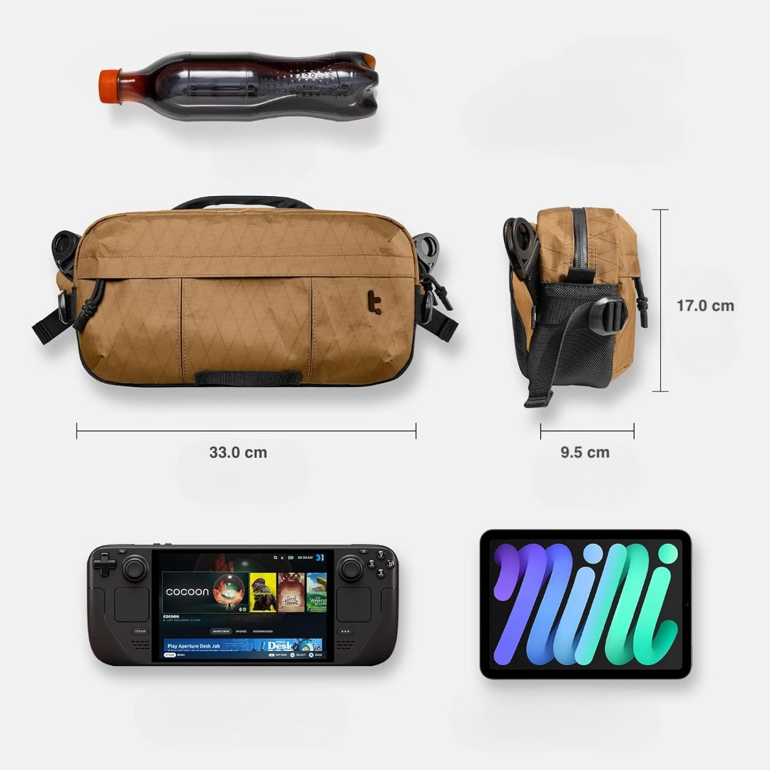 Układ technologii i akcesoriów: torba, napój, konsola przenośna, tablet. Podano wymiary szerokości i wysokości torby.