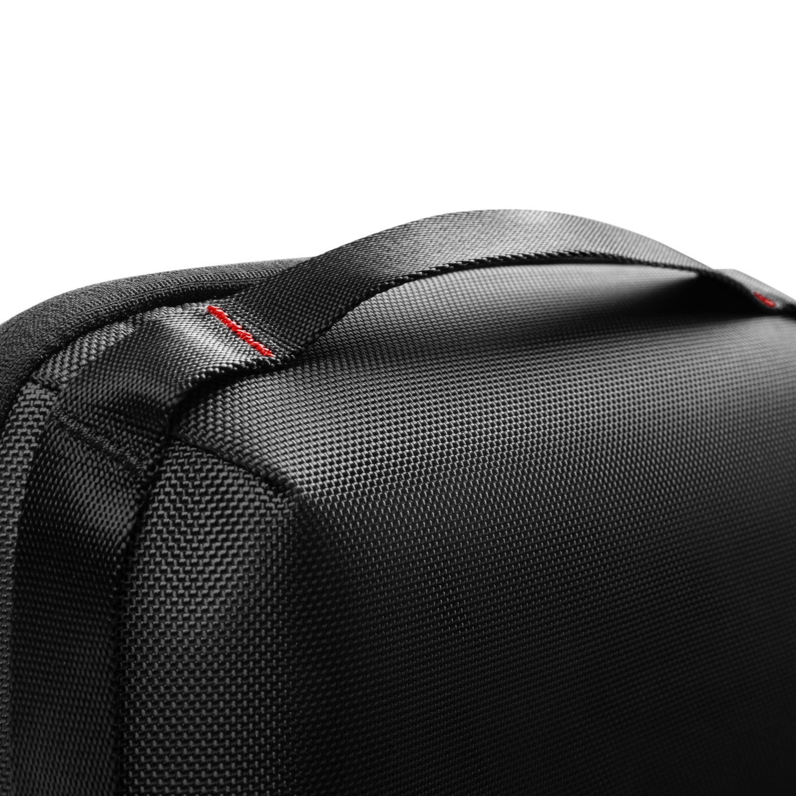 Zbliżenie czarnego, teksturowanego uchwytu torby. Czerwone przeszycia podkreślają szew. Białe tło.