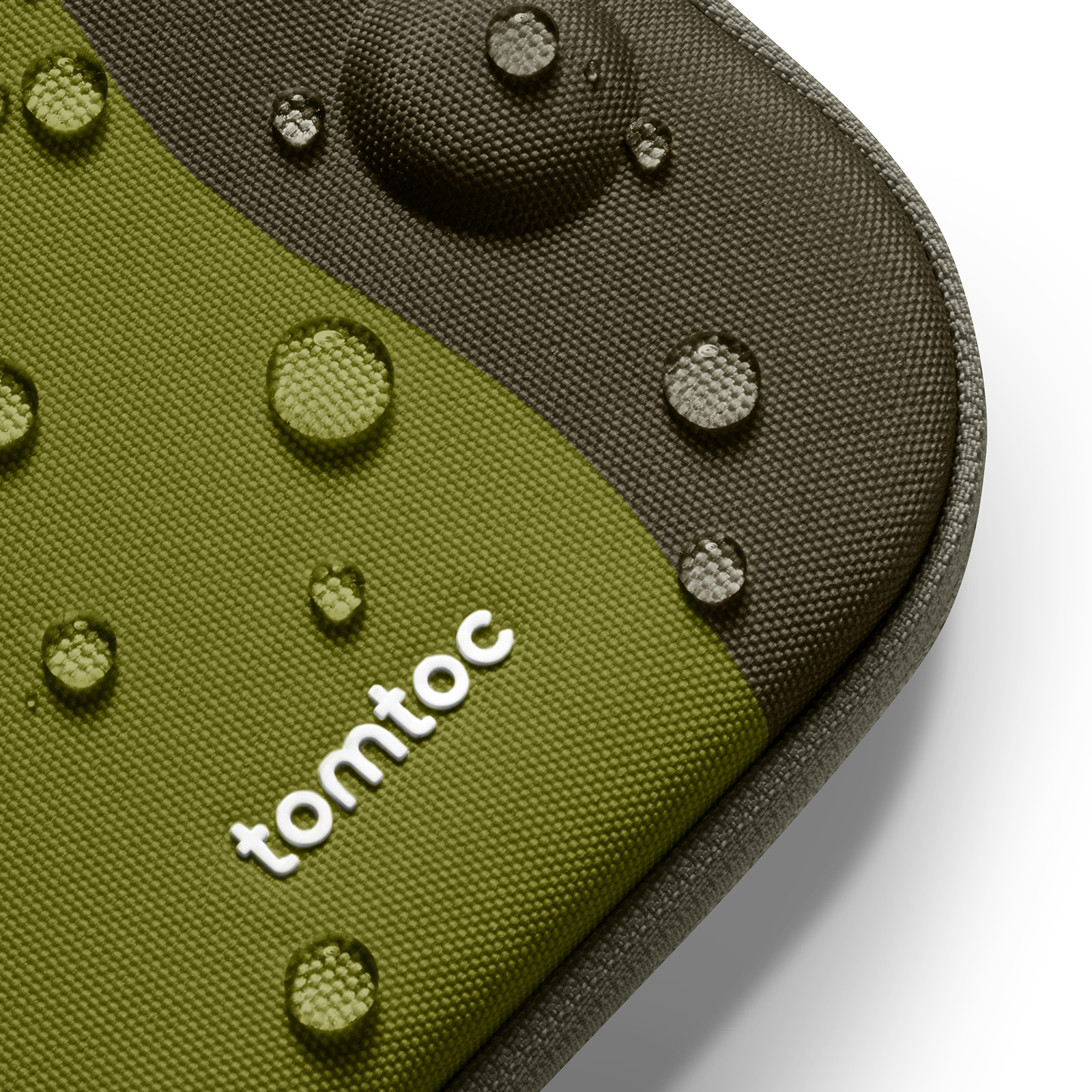 Zbliżenie zielonej i szarej powierzchni materiału z kroplami wody. Widoczne białe logo 'tomtoc'. Białe tło.