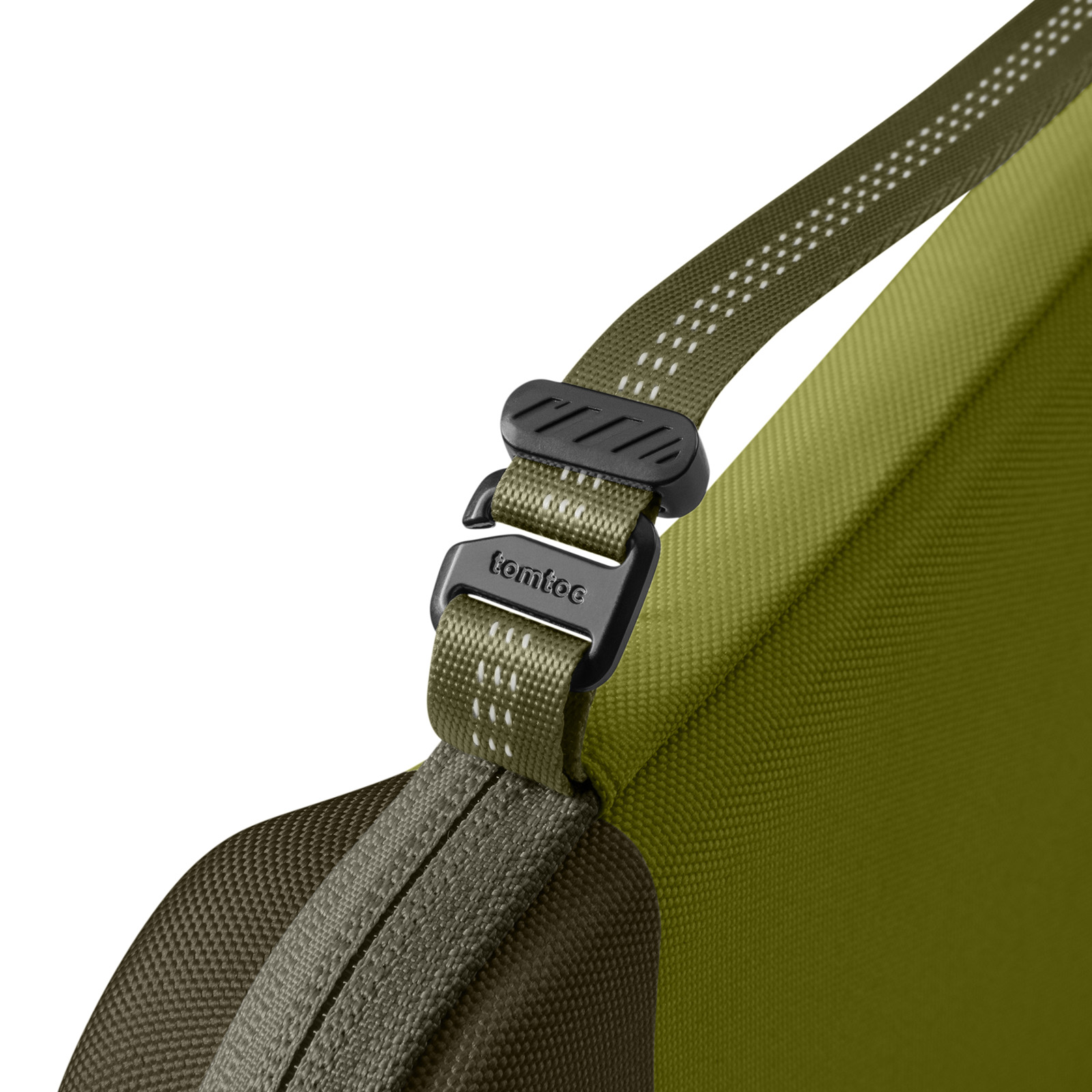 Zbliżenie zielonego paska torby z czarną klamrą. Widoczna nazwa marki 'tomtoc'. Białe kropki na pasku.
