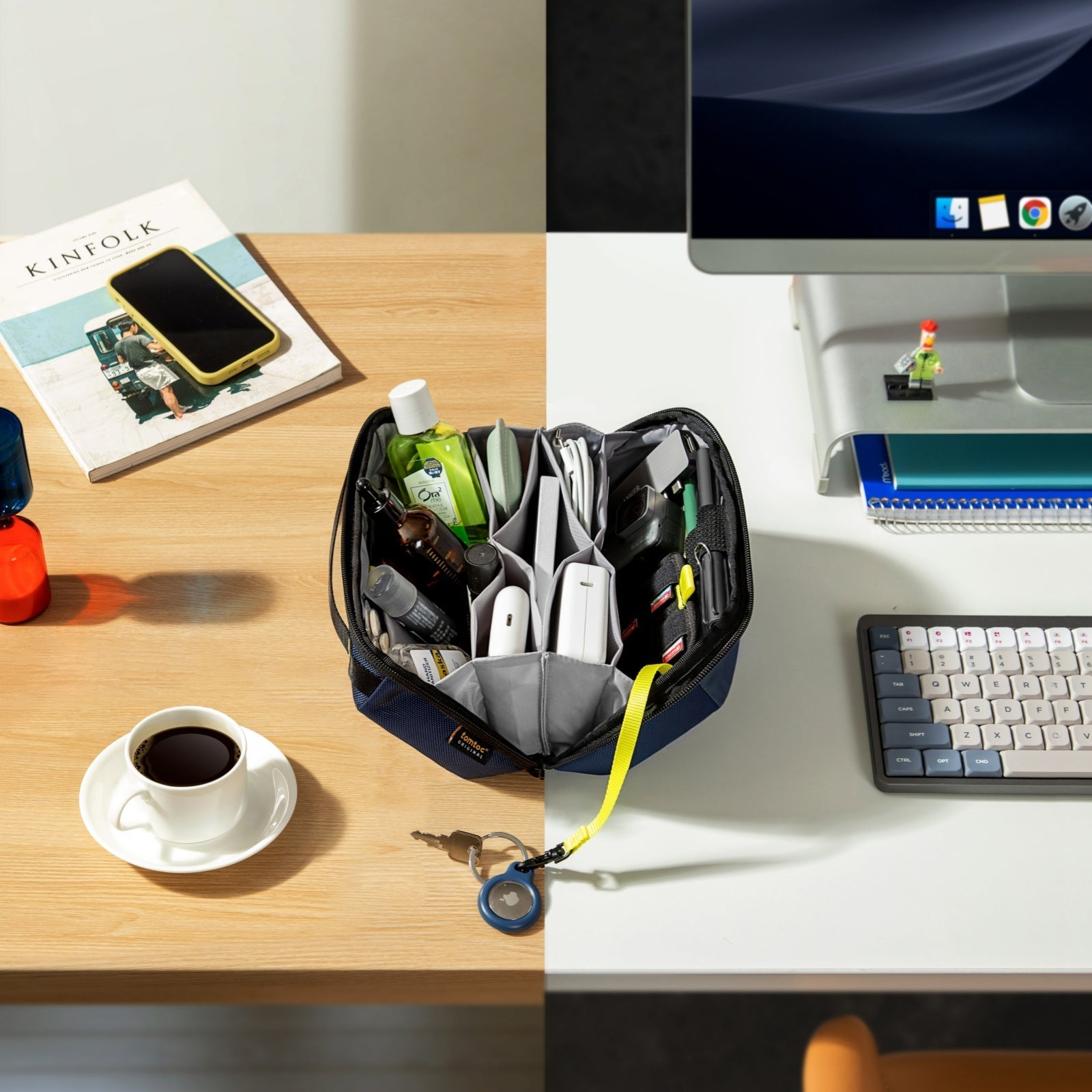 Podzielone biurko pokazuje przedmioty. Lewa: kawa, telefon, magazyn i torba. Prawa: monitor, klawiatura, figurka Lego i torba.