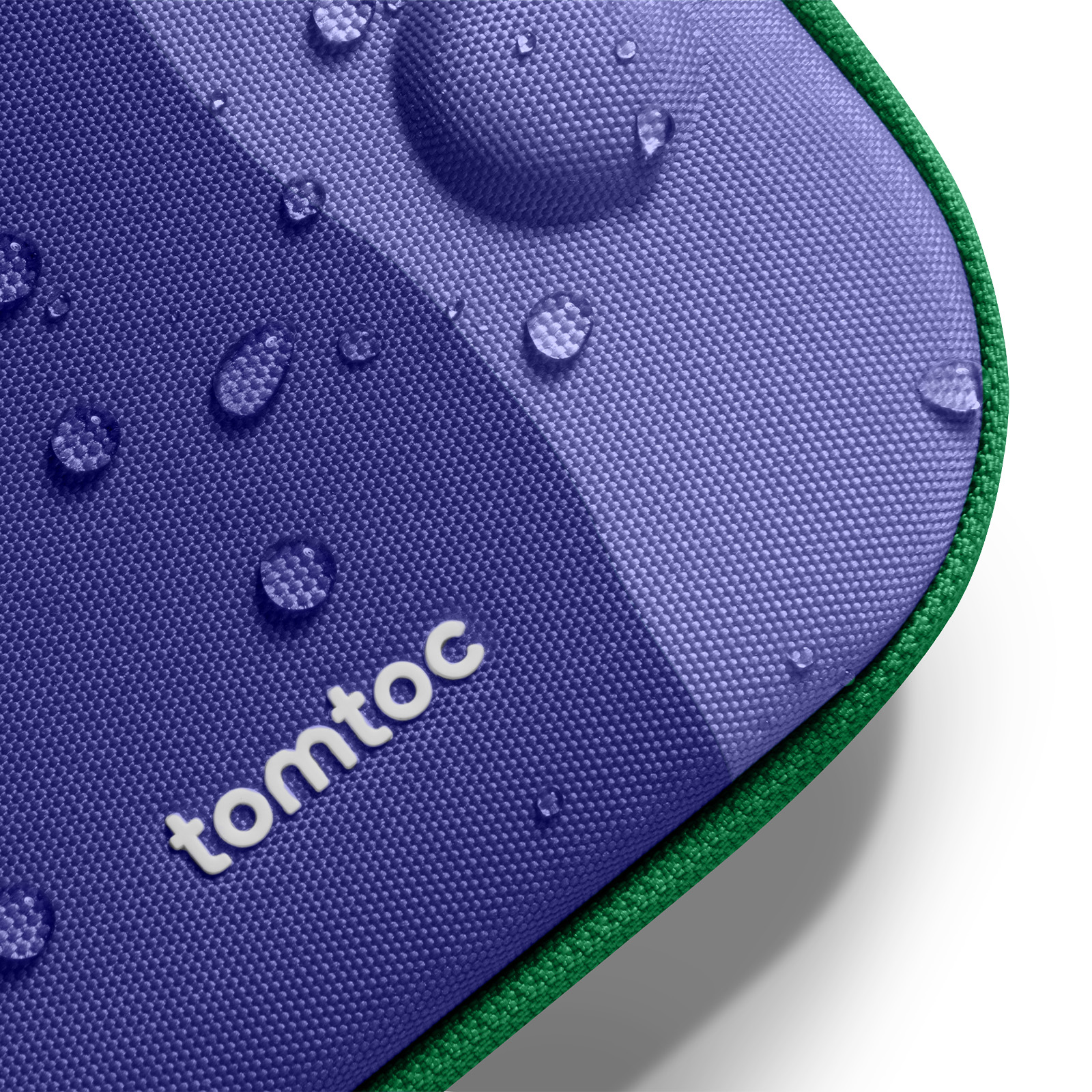 Zbliżenie fioletowego etui z kroplami wody. Etui ma zieloną obwódkę i napis 'tomtoc'.