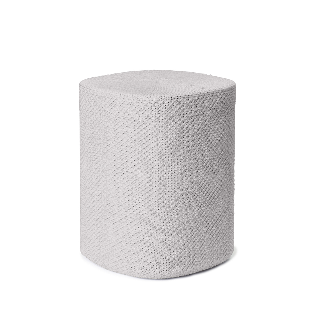 Un pouf cylindrique gris clair sur fond blanc. Il présente une surface texturée et tissée et des bords arrondis.