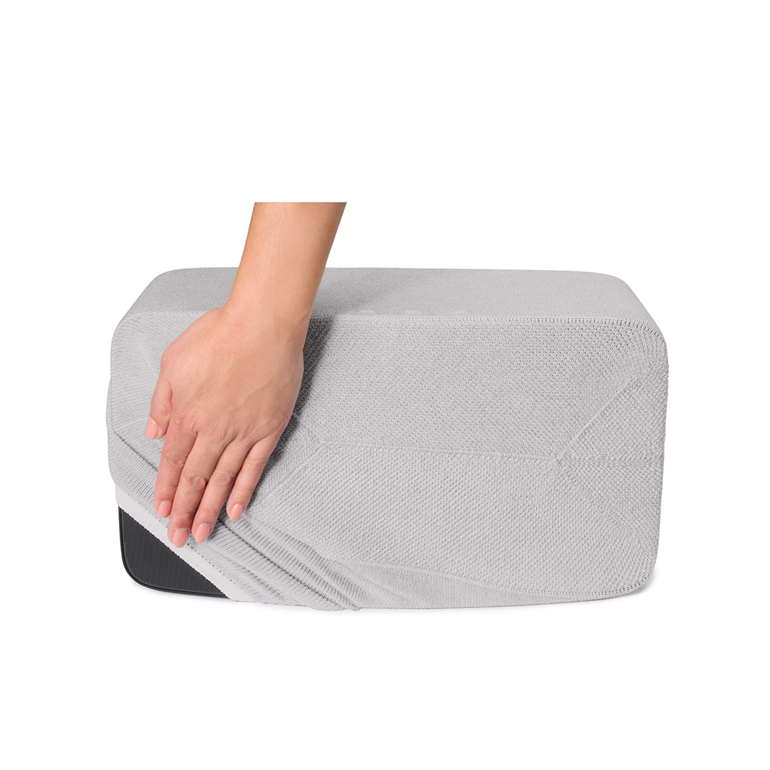 Une main tire une couverture gris clair d'un objet rectangulaire. L'objet a un fond plus foncé.