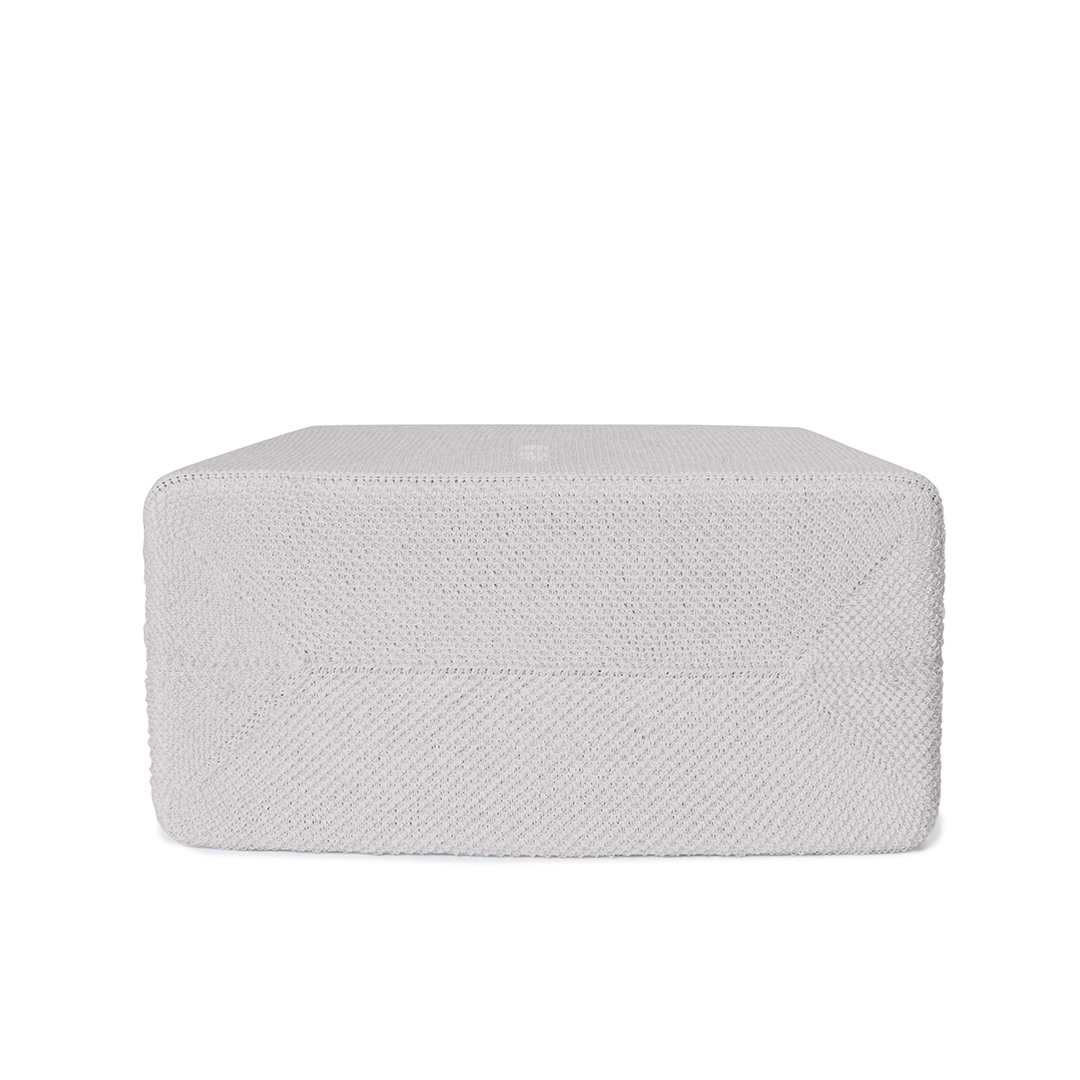 Un pouf rectangulaire gris clair sur fond blanc. Le pouf a un aspect texturé et tricoté.