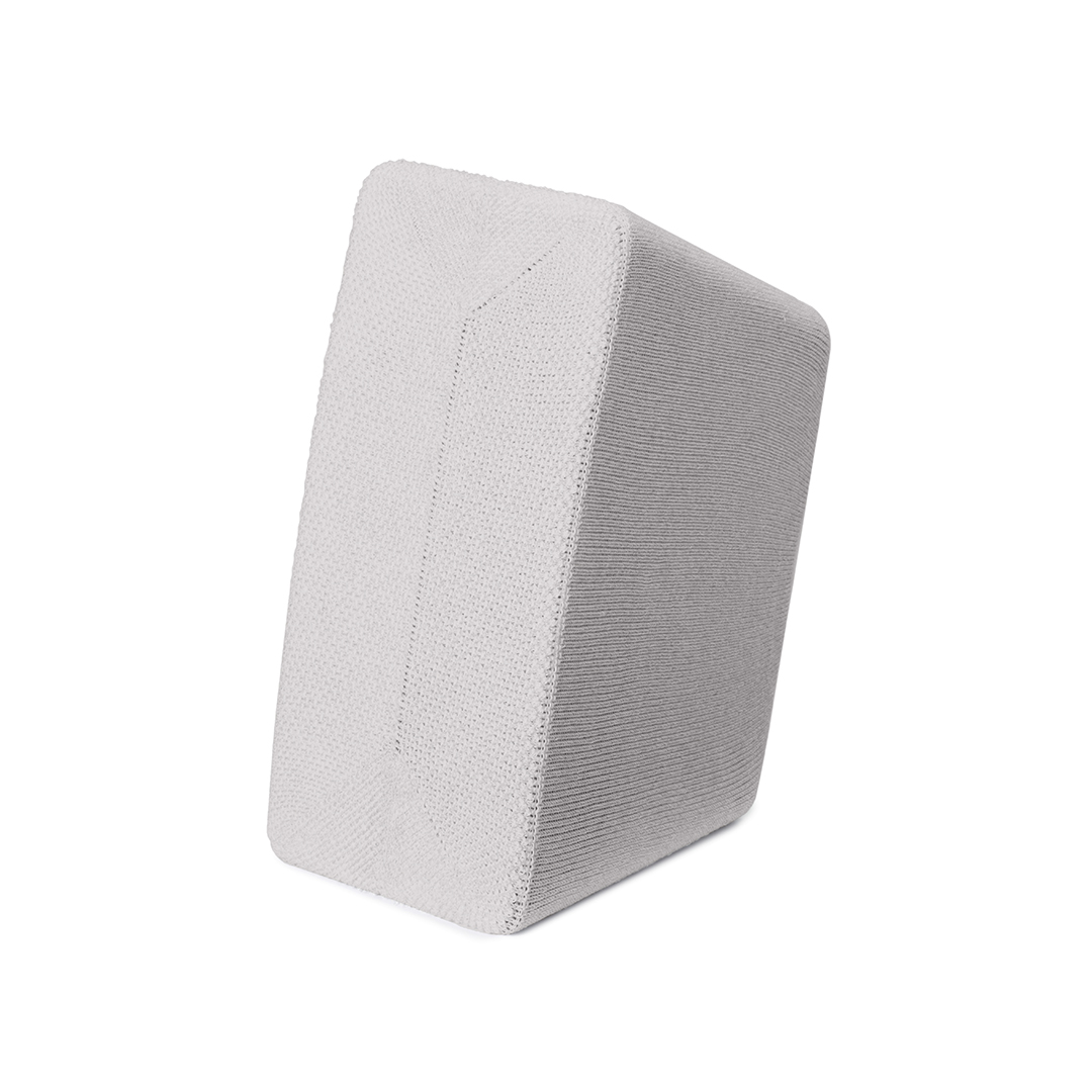 Un objet rectangulaire gris et blanc. L'objet est incliné, montrant un côté blanc texturé et un côté gris côtelé. Le fond est blanc.