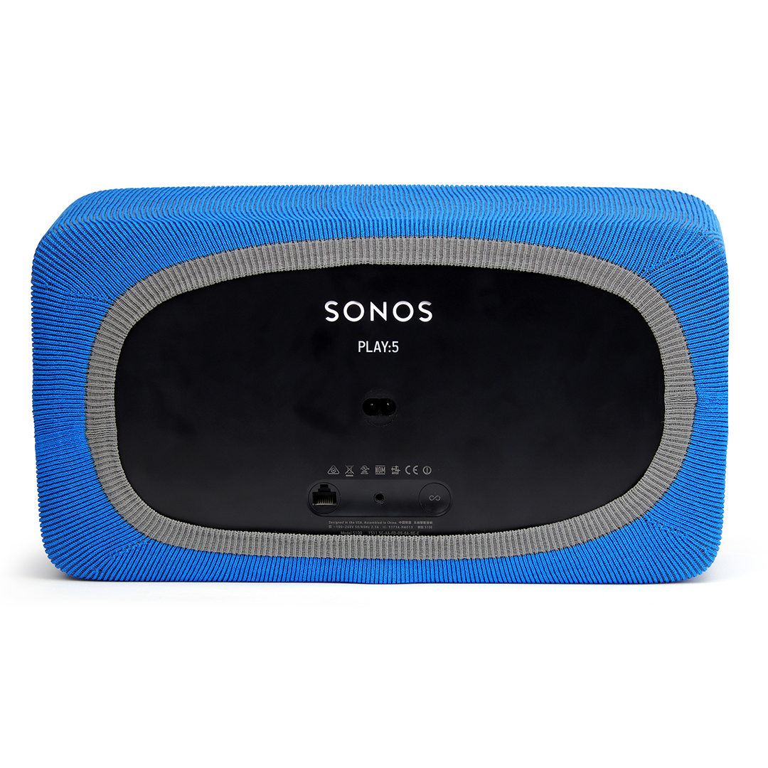 L'arrière d'un haut-parleur Sonos PLAY:5. Il a une housse en tissu bleu avec une bordure grise, un centre noir et le logo Sonos.