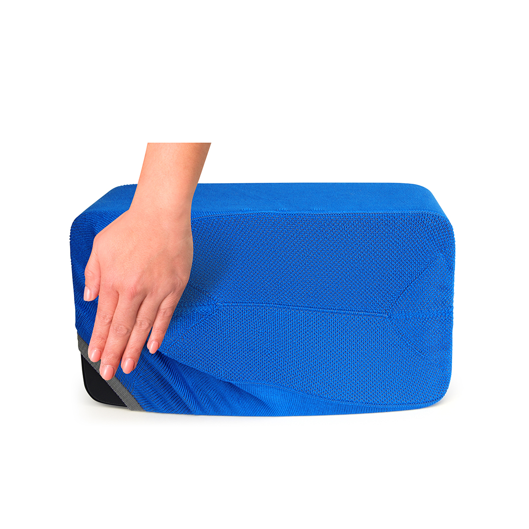 Une main tire un tissu bleu d'un objet rectangulaire. L'objet a un bord noir et gris.
