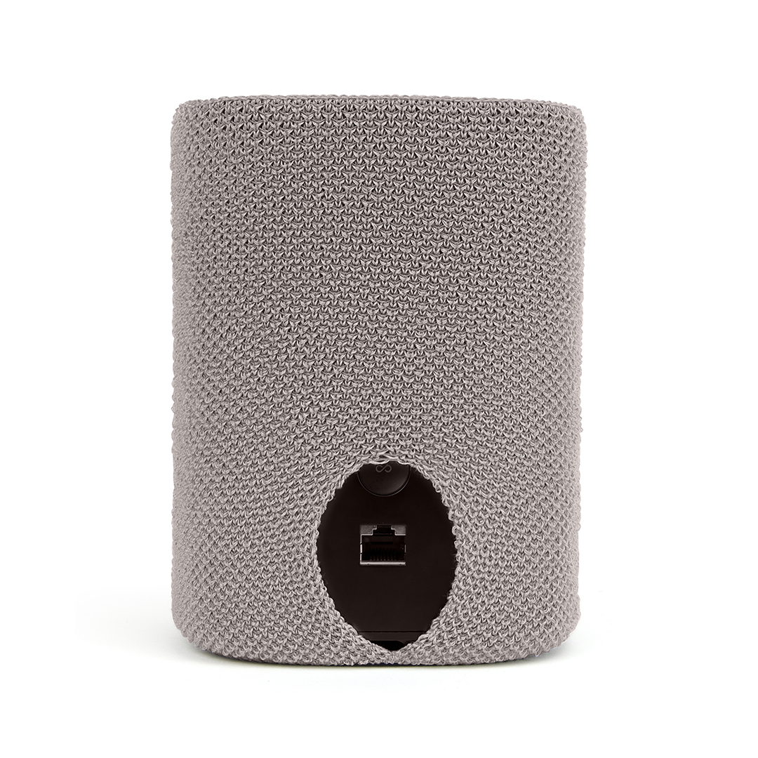 Un appareil cylindrique recouvert d'un tissu en tricot gris, montrant un port noir. Le fond est blanc.