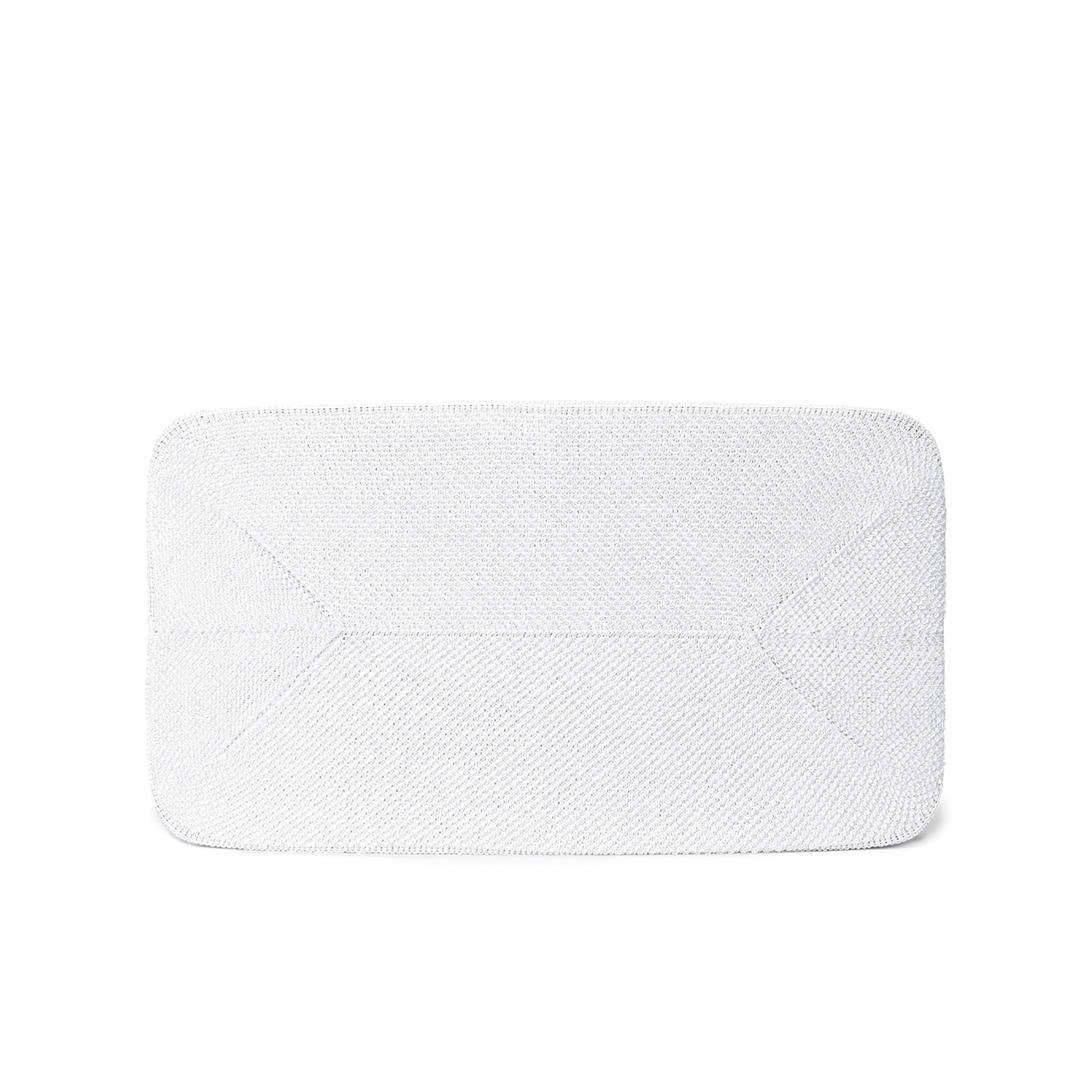 Un objet blanc rectangulaire aux coins arrondis, peut-être un sac, repose sur un fond blanc. La surface présente un motif texturé.