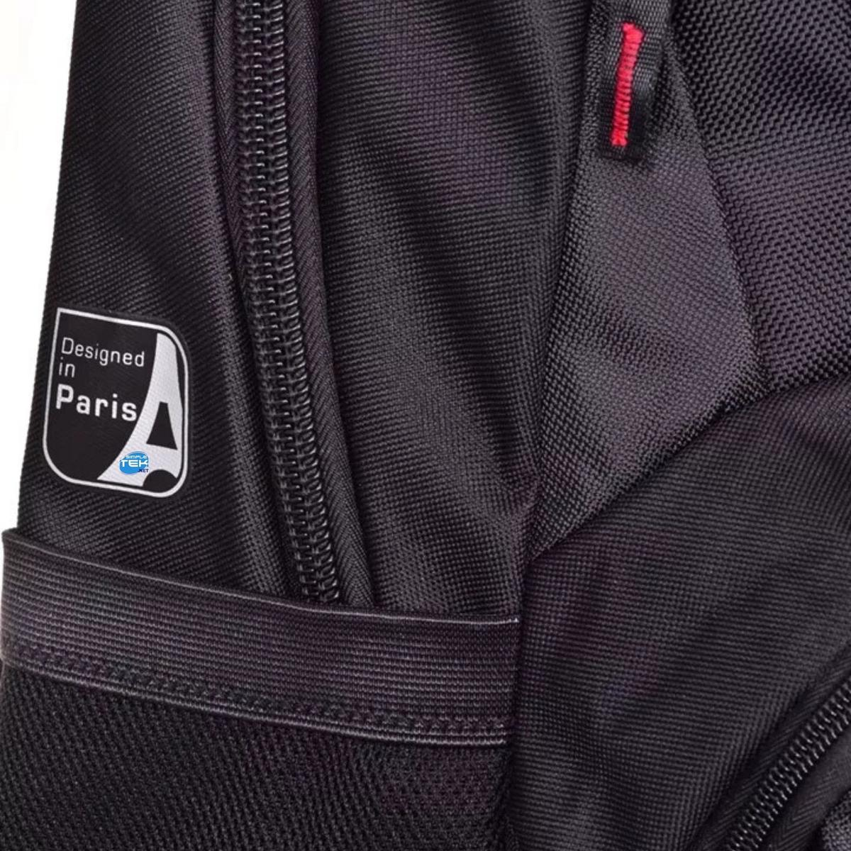 Close-up of a black bag with a 'Designed in Paris' logo. A red stitch detail is visible. The bag has a zipper and strap.