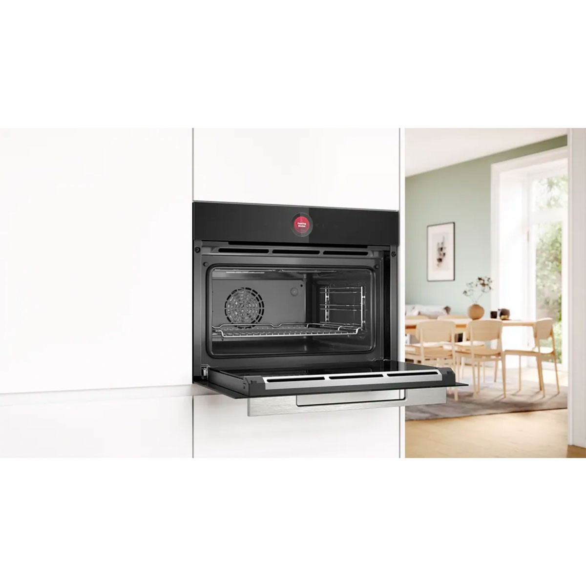 Open oven in witte keuken. Ovendeur open, roestvrijstalen interieur. Achtergrond, lichtgroene kamer met tafel en stoelen.