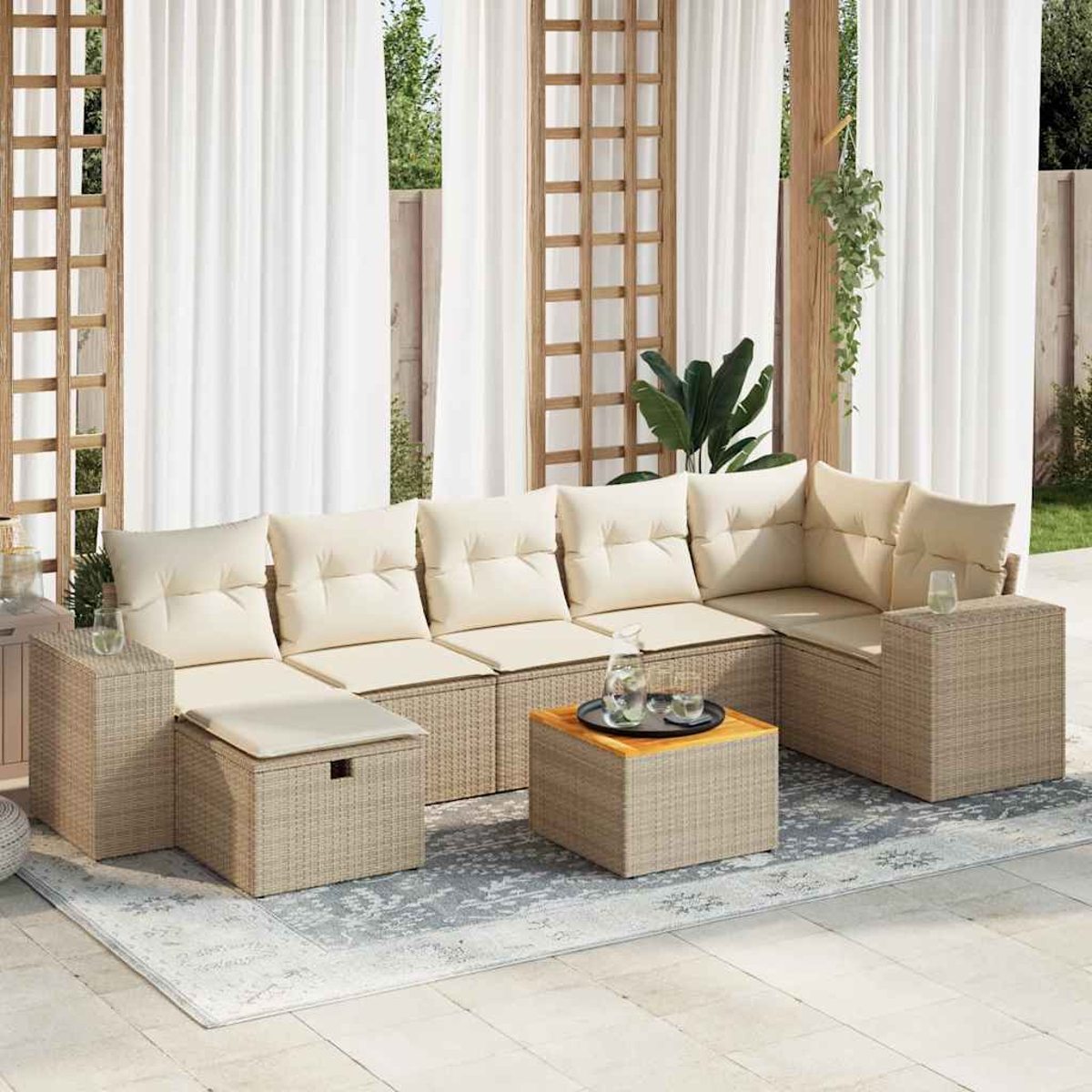 Sedute all'aperto con cuscini beige, tavolo in legno con vassoio, tende bianche e tappeto. Piante e traliccio in legno sullo sfondo.