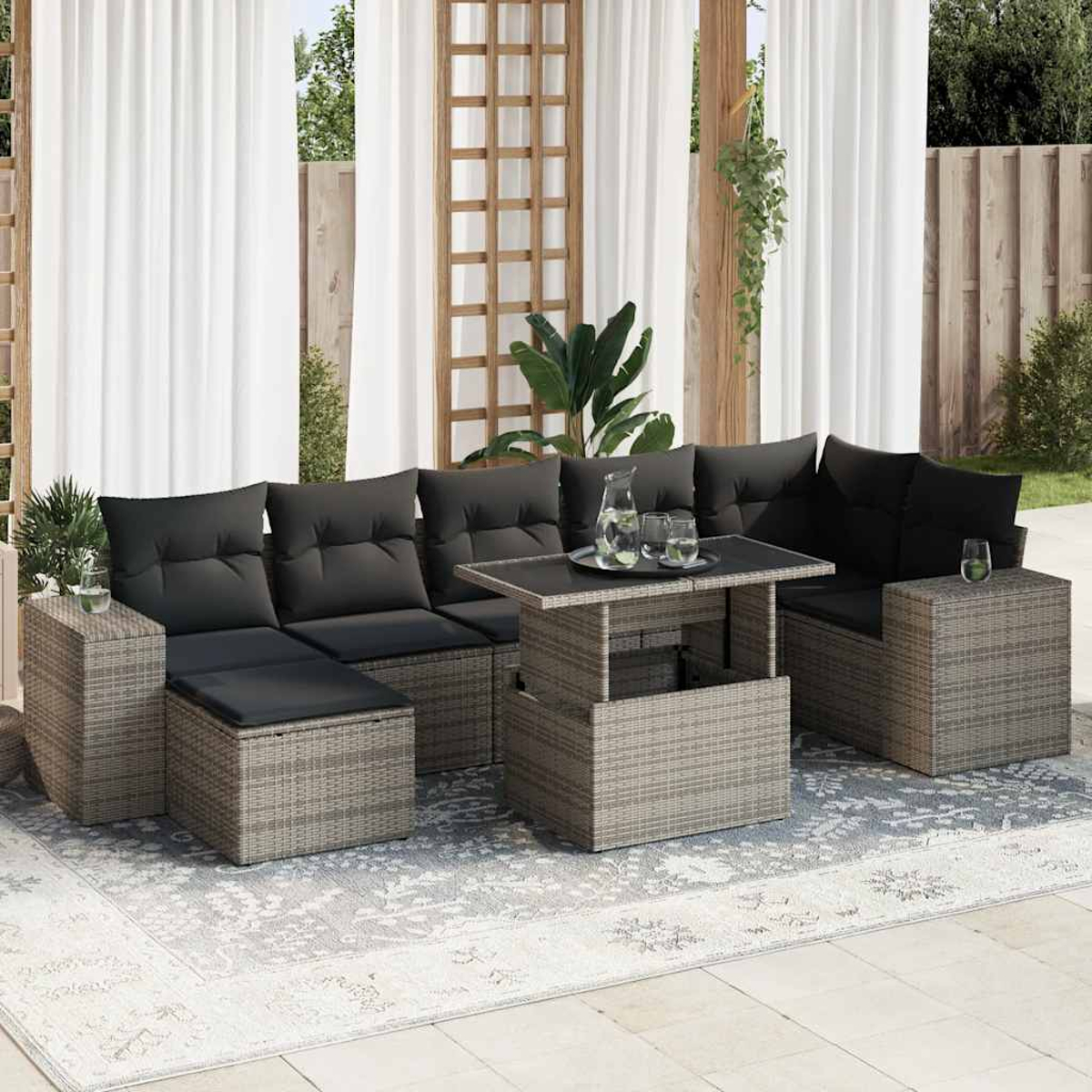 Set di divani da esterno con cuscini grigi, tavolino, tavolini e tappeto. Lo sfondo ha tende e traliccio in legno.