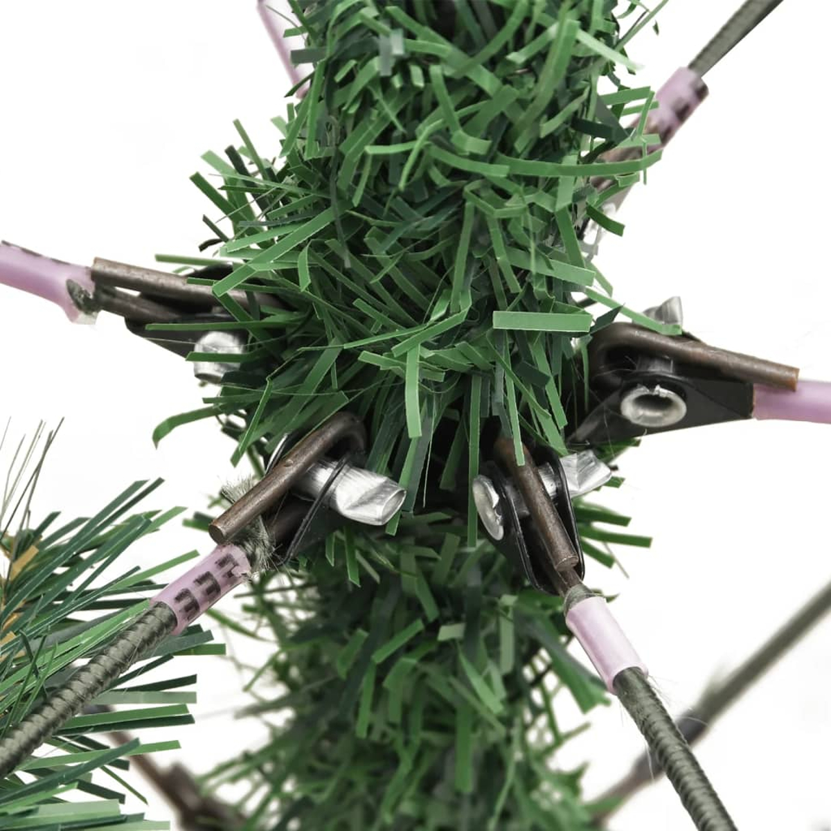 Nahaufnahme eines Weihnachtsbaumdetails. Grüne Nadeln, braune Metallhaken und rosa Stützen sind vor weißem Hintergrund zu sehen.