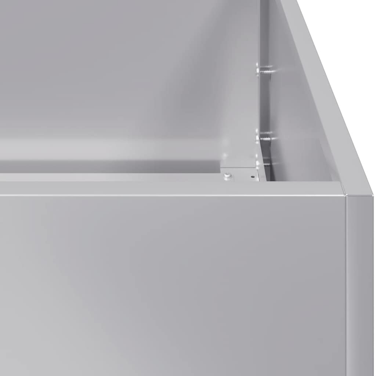 Primo piano di una scatola di metallo grigio. La scatola ha angoli vivi e viti visibili. Lo sfondo è grigio pieno.
