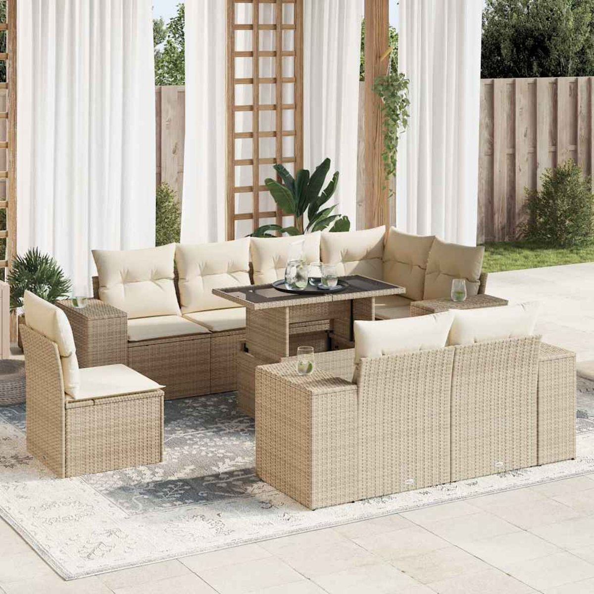 Set di mobili da esterno in vimini con cuscini color crema, un tavolo con bicchieri e tende bianche creano un'atmosfera da patio.