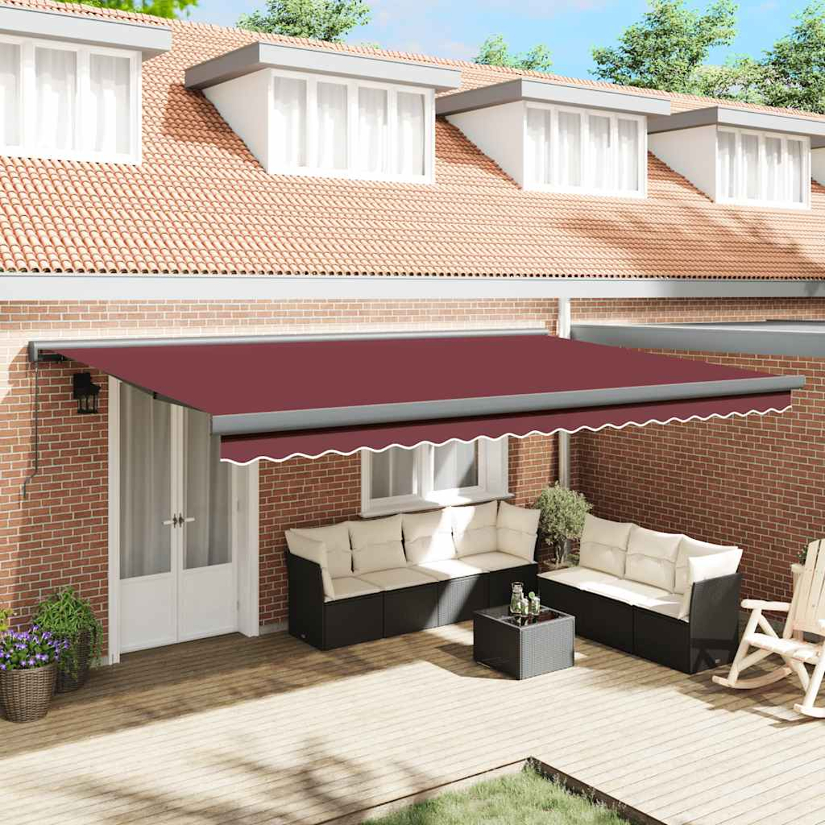 Una tenda da sole rossa copre i posti a sedere all'aperto. Sfondo di muro di mattoni con finestre e tetto di tegole. Mobili da patio su una terrazza di legno.