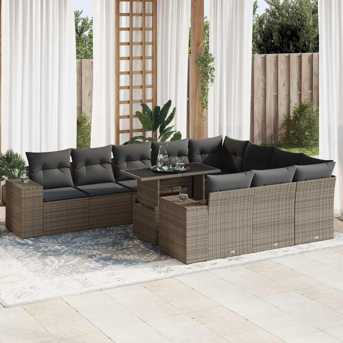 Set da patio esterno con cuscini grigi. Presenta un tavolo, un divano e tende. Il pavimento è piastrellato.