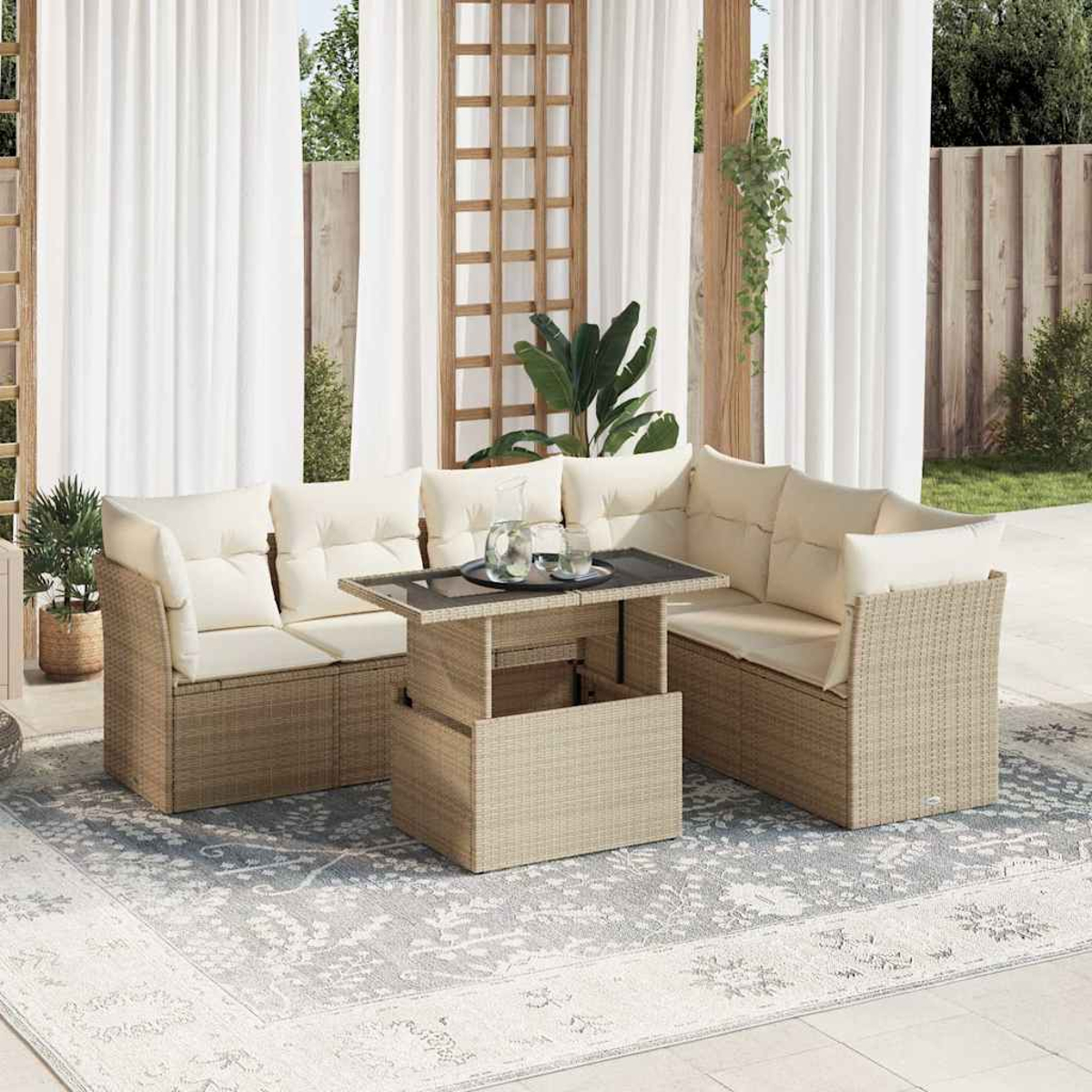 Set di sedute in vimini per esterni con cuscini, un tavolo con bevande e un tappeto fantasia su un patio. Tende bianche sullo sfondo.