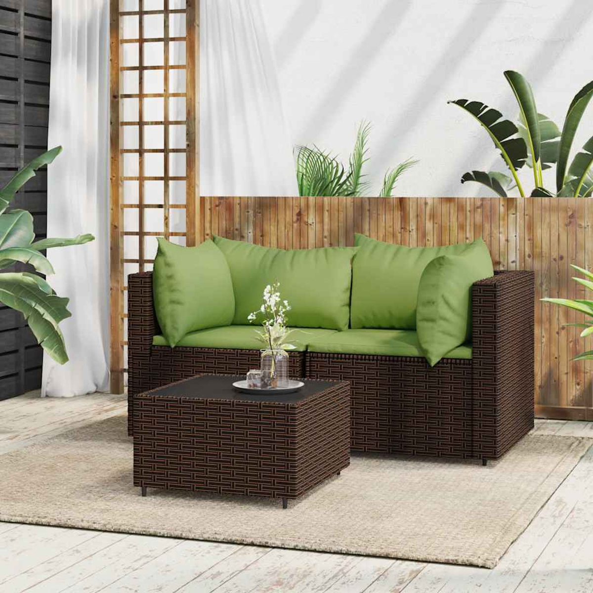 Outdoor-Wicker-Sofa mit grünen Kissen, passendem Couchtisch und Pflanzen im Hintergrund. Eine gemütliche Umgebung im Freien.