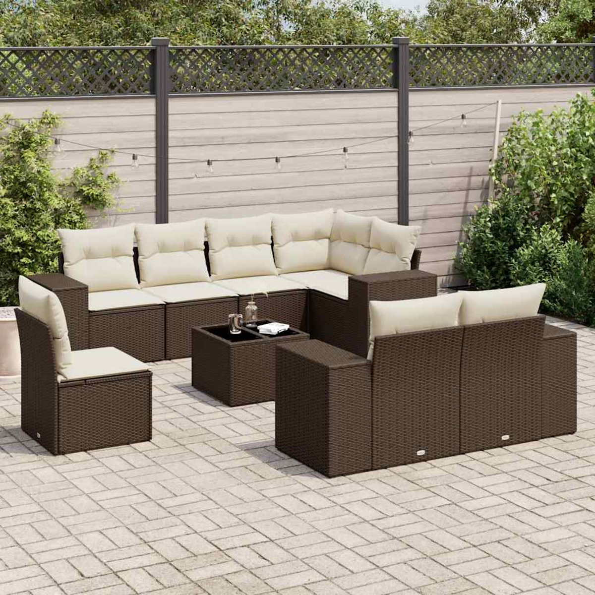 Set da patio esterno. Mobili in vimini marrone con cuscini color crema. Include un divano componibile, sedie e un tavolo. Su un patio in pietra.