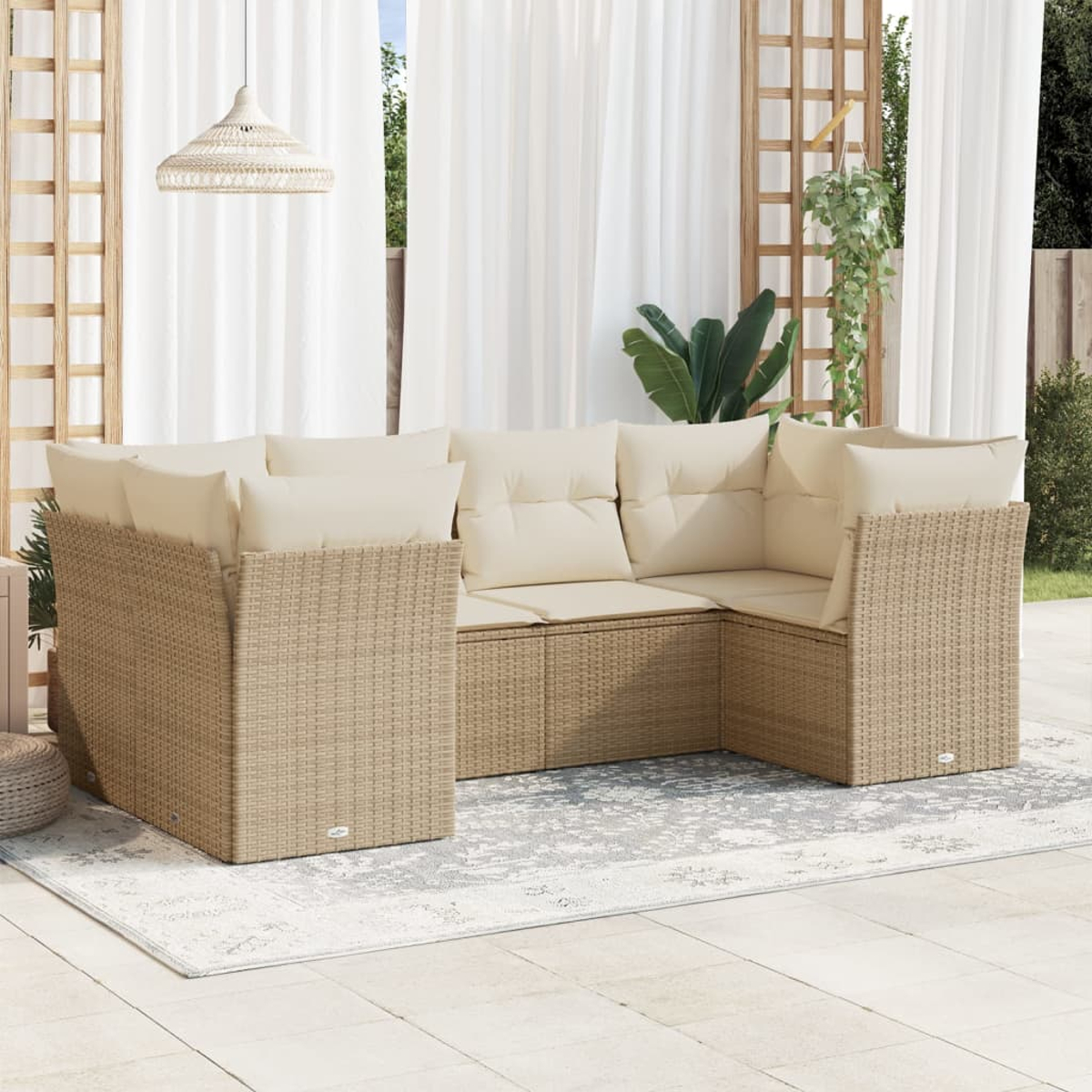 Divano angolare da esterno con cuscini beige. Struttura in tessuto beige. Tende bianche e una lampada intrecciata sullo sfondo. Tappeto grigio sul patio.