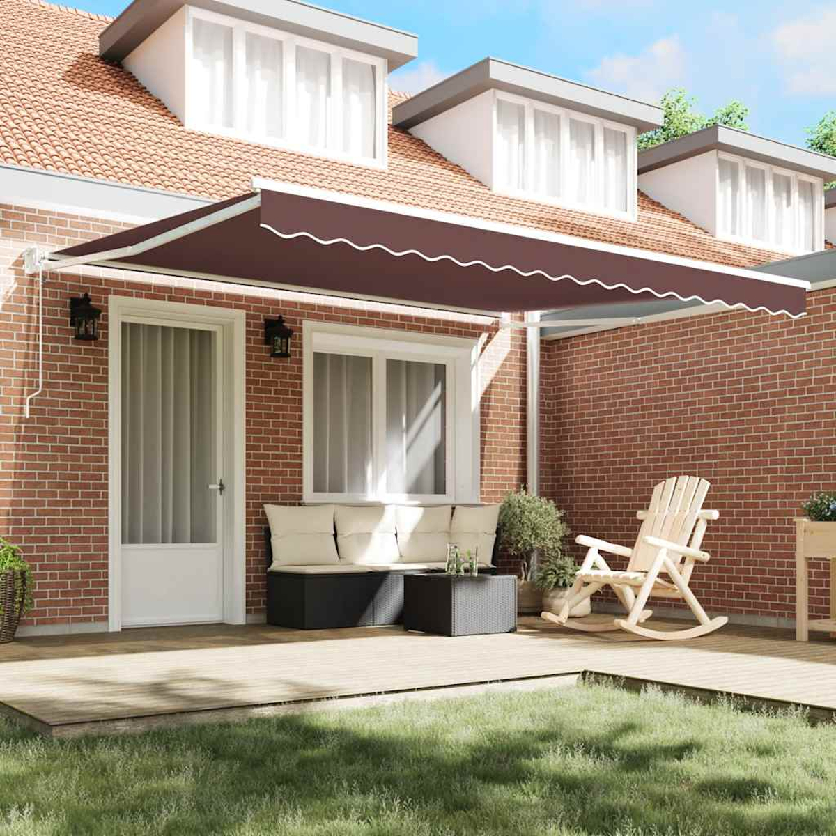 Ein Haus mit brauner Markise. Es gibt eine Sitzecke mit Sofa und Schaukelstuhl. Grünes Gras ist im Vordergrund.