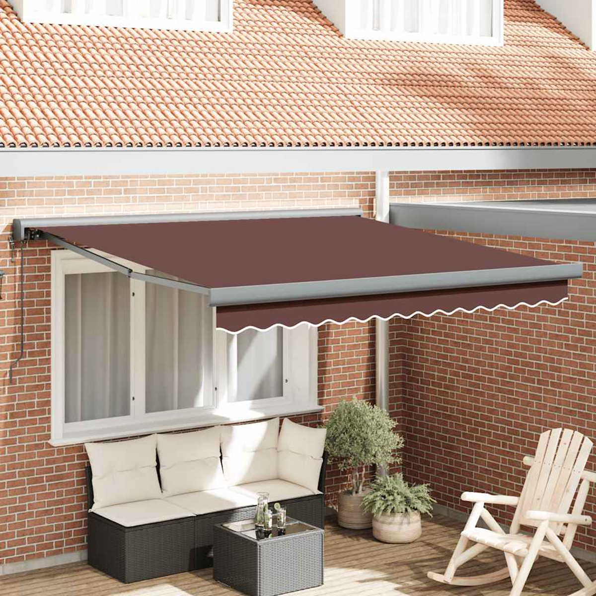 Una tenda da sole marrone sopra una finestra, con un set da patio sottostante. Muro di mattoni e tetto di tegole sullo sfondo. C'è una sedia a dondolo.