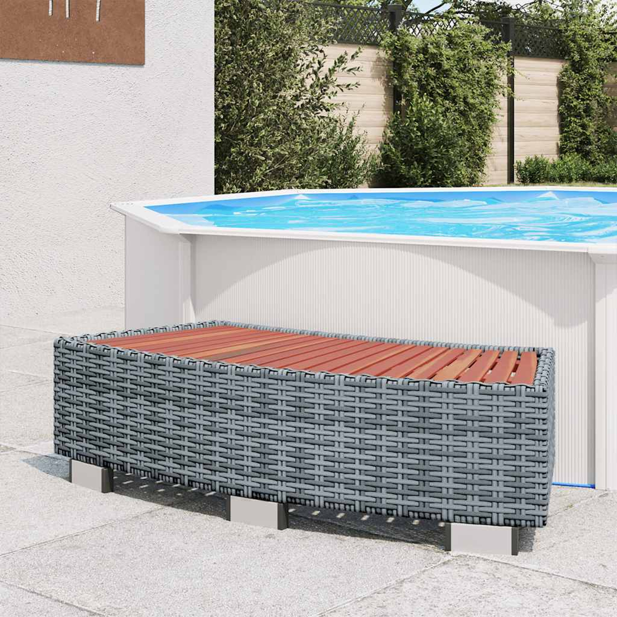 Eine graue Korbbank mit Holzplatte steht vor einem Pool. Grüne Büsche im Hintergrund, weiße Wand links.