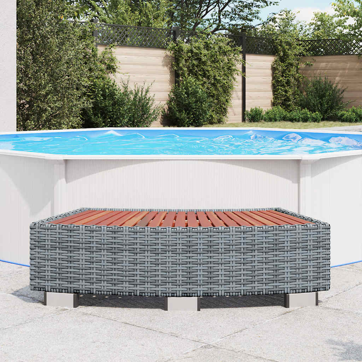 Eine Hinterhofszene mit Pool und grauem Korbtisch. Der Pool hat blaues Wasser. Grüne Bäume und ein Zaun sind im Hintergrund.