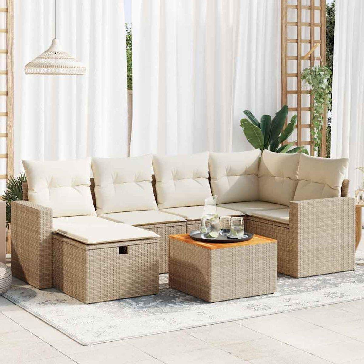 Ein beiges Outdoor-Ecksofa aus Korbgeflecht mit cremefarbenen Kissen, ein kleiner Tisch mit Getränken und weiße Vorhänge im Hintergrund.