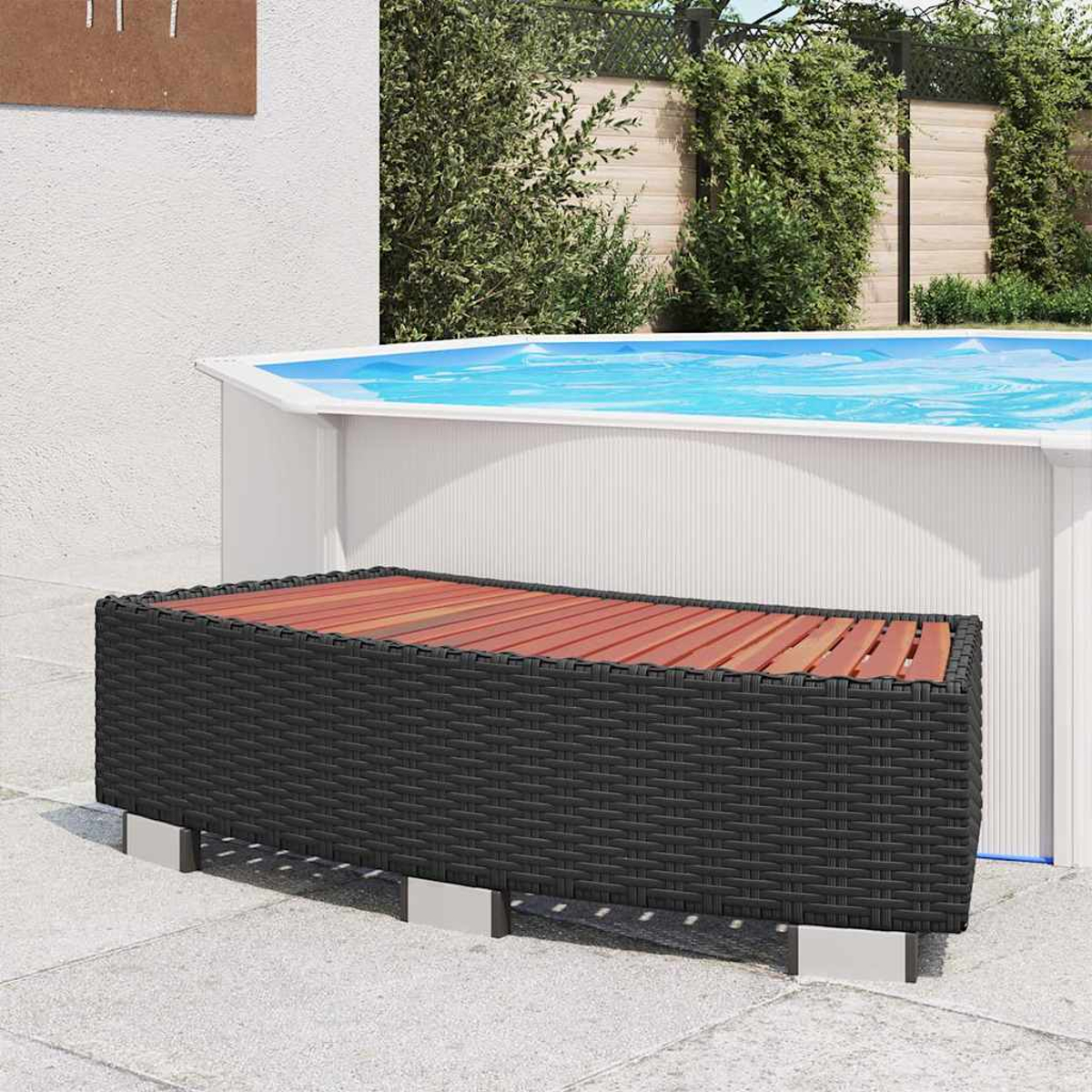 Eine schwarze gewebte Bank mit Holzplatte steht vor einem Pool. Im Hintergrund sind grüne Büsche.