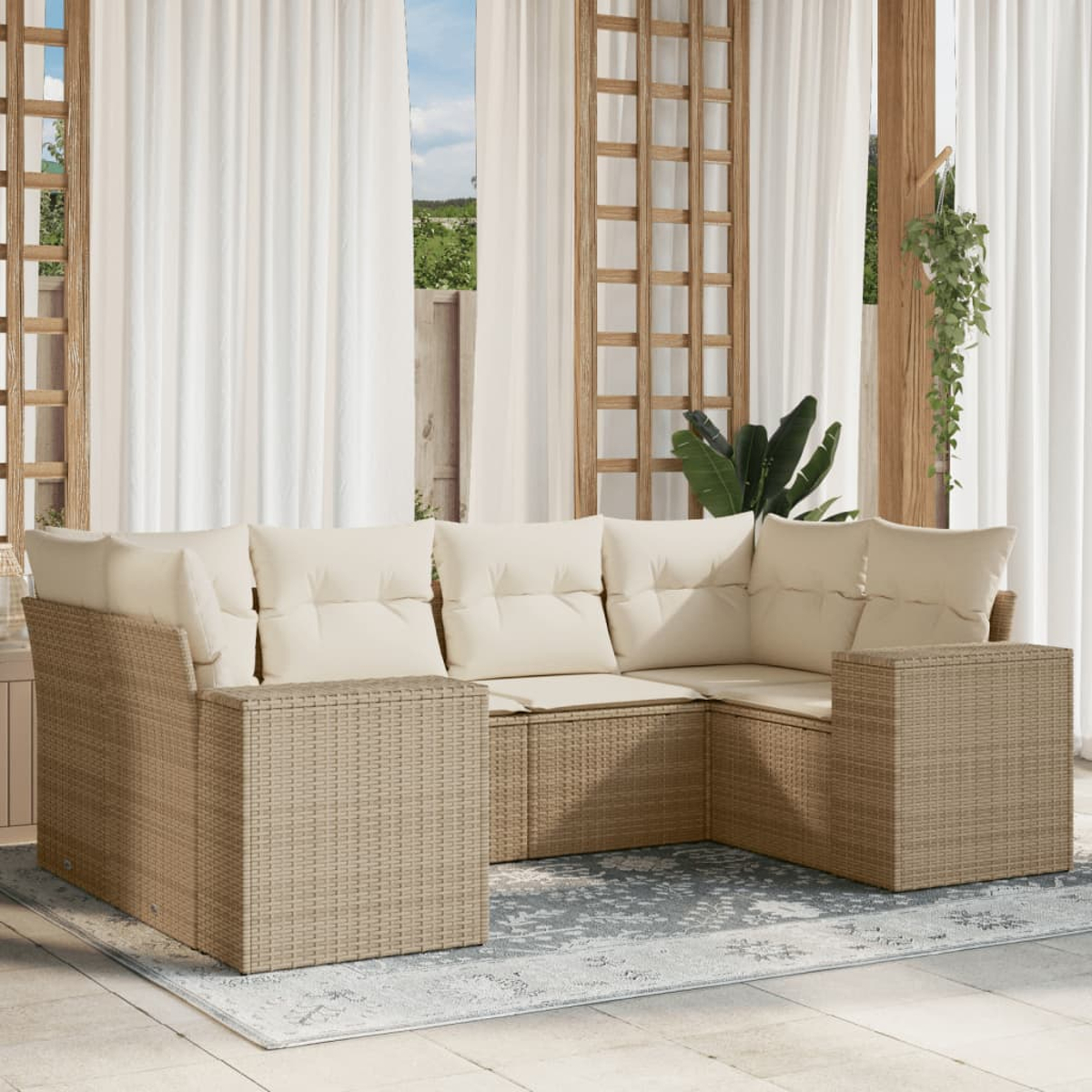 Ein beiges Outdoor-Ecksofa aus Korbgeflecht mit cremefarbenen Kissen steht auf einem Teppich. Transparente weiße Vorhänge und Holzgitter rahmen die Szene ein.