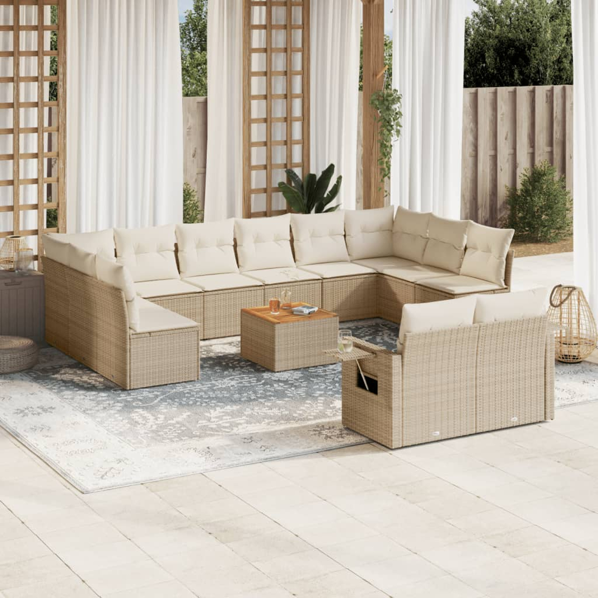 Area salotto esterna con mobili in vimini e cuscini color crema, un tappeto e tende trasparenti. Un tavolino ha delle bevande.