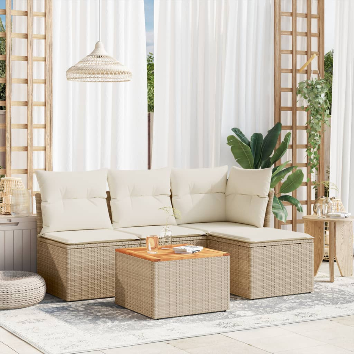 Outdoor-Sitzbereich mit Korbmöbeln, Kissen, Couchtisch und Hängelampe vor weißen Vorhängen.