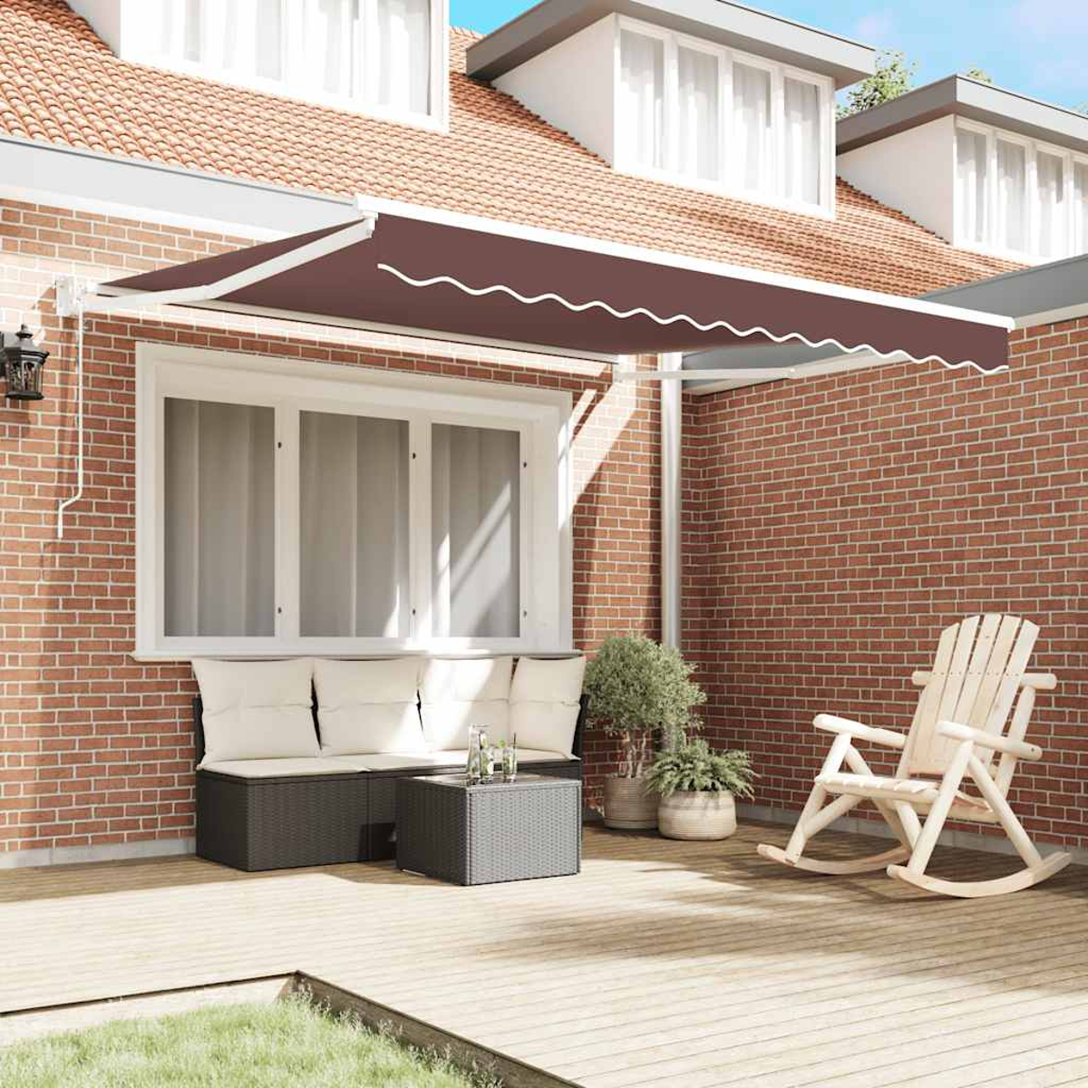 Un patio con tenda da sole marrone, sedia a dondolo bianca e muro di mattoni. Sono presenti anche un divano, un tavolo e delle piante.