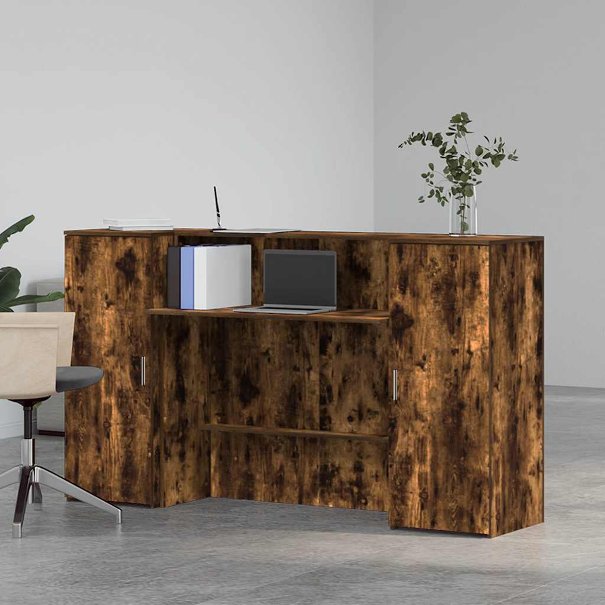 Ein Empfangstresen aus Holz mit Laptop, Büchern und Pflanze. Ein Stuhl ist im Vordergrund.