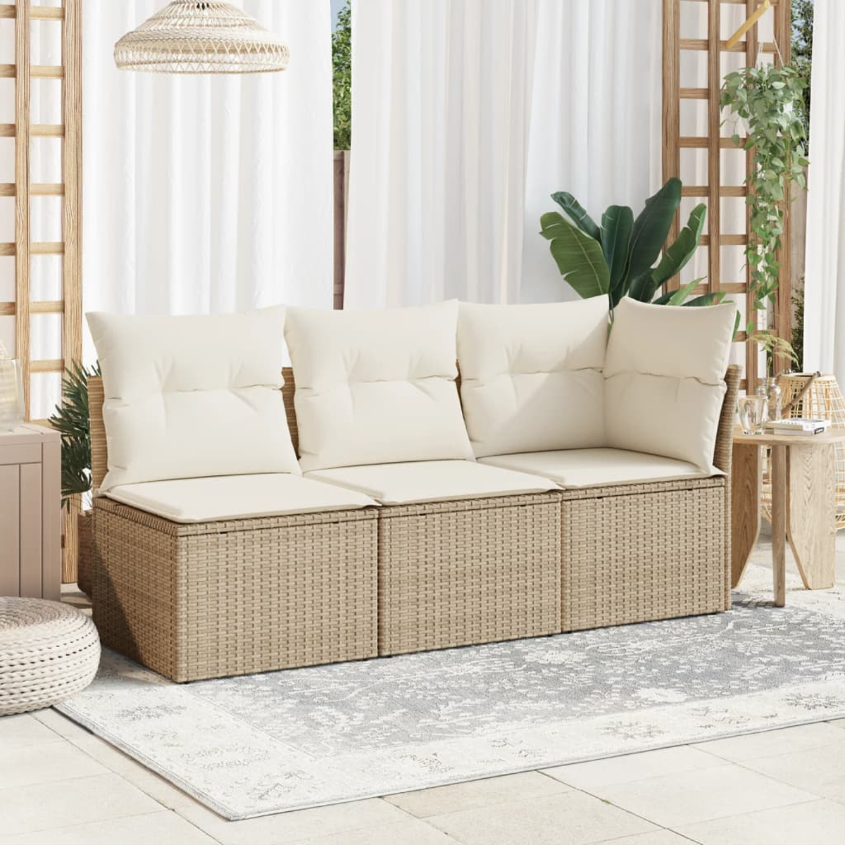 Divano in rattan con cuscini color crema su un patio con un tappeto fantasia. Tende bianche e piante decorative sullo sfondo.