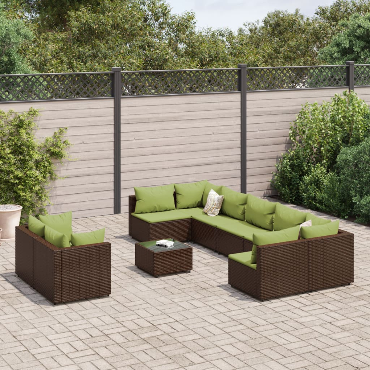 Garten-Terrassenset mit braunen Korbmöbeln, grünen Kissen und einem kleinen Tisch, auf einer Steinpflasterung mit Laub im Hintergrund.