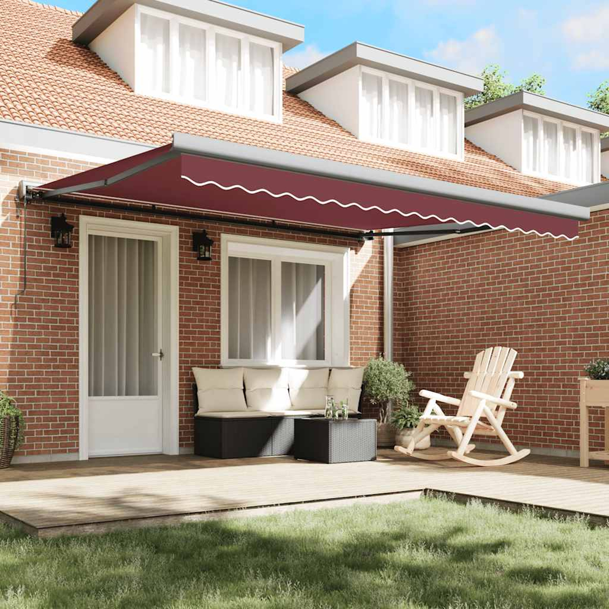Una tenda da sole rossa sopra un patio, con una sedia a dondolo e un divano. Un muro di mattoni e una casa con finestre sullo sfondo.