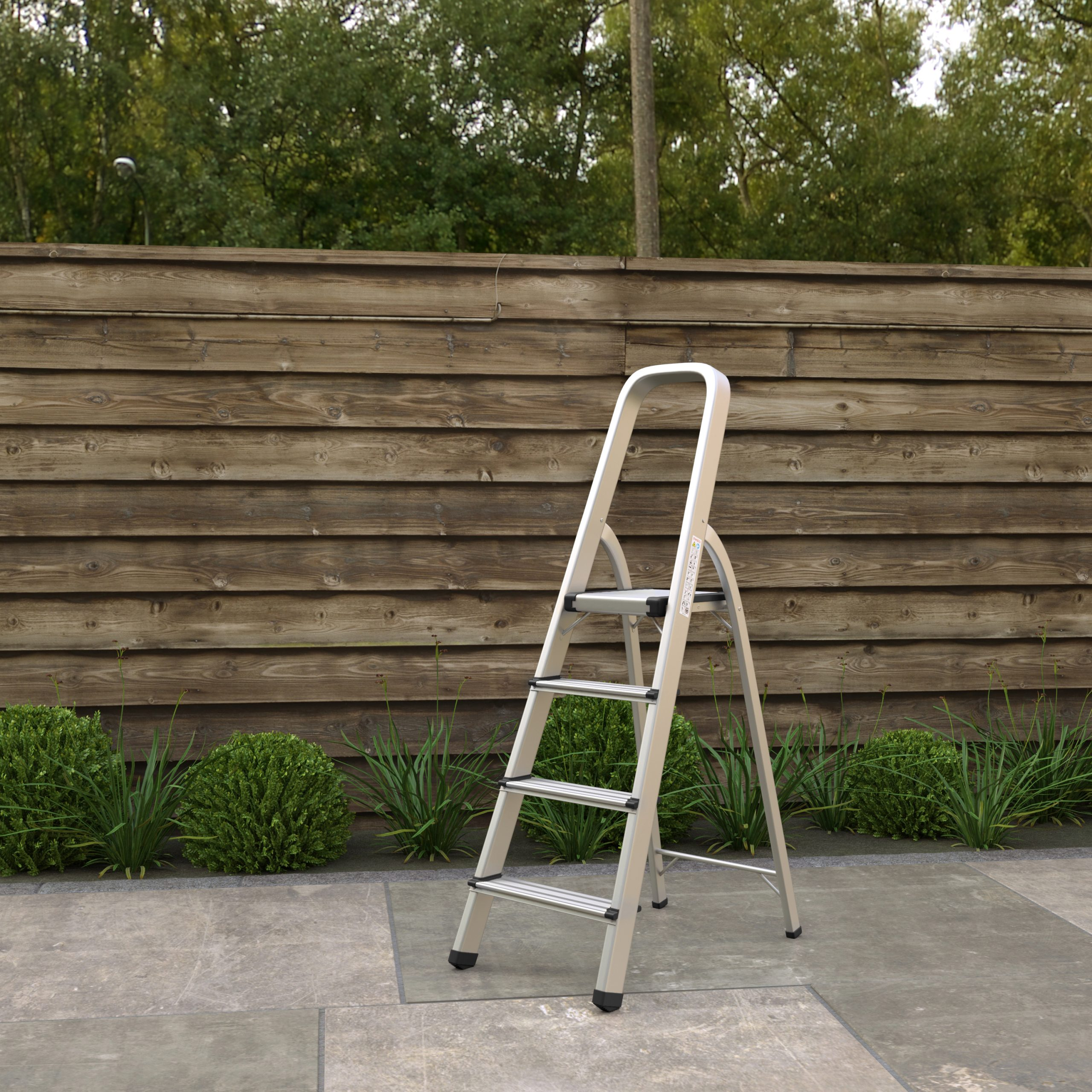 A silver ladder stands on a stone patio. A wooden fence and green bushes are in the background.