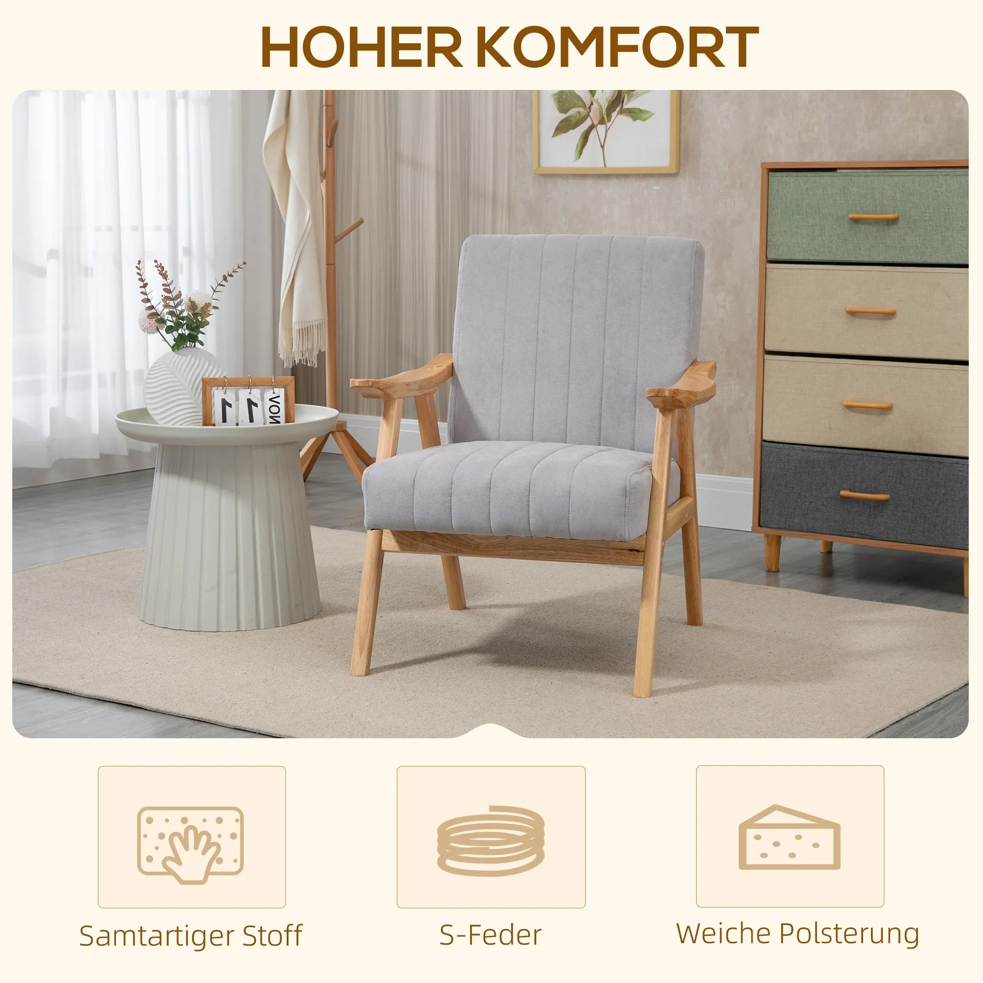 Ein grauer Sessel mit Holzarmlehnen steht in einem Raum mit einem Beistelltisch, Blumen und einer Kommode. Der Stuhl hat eine weiche Polsterung.