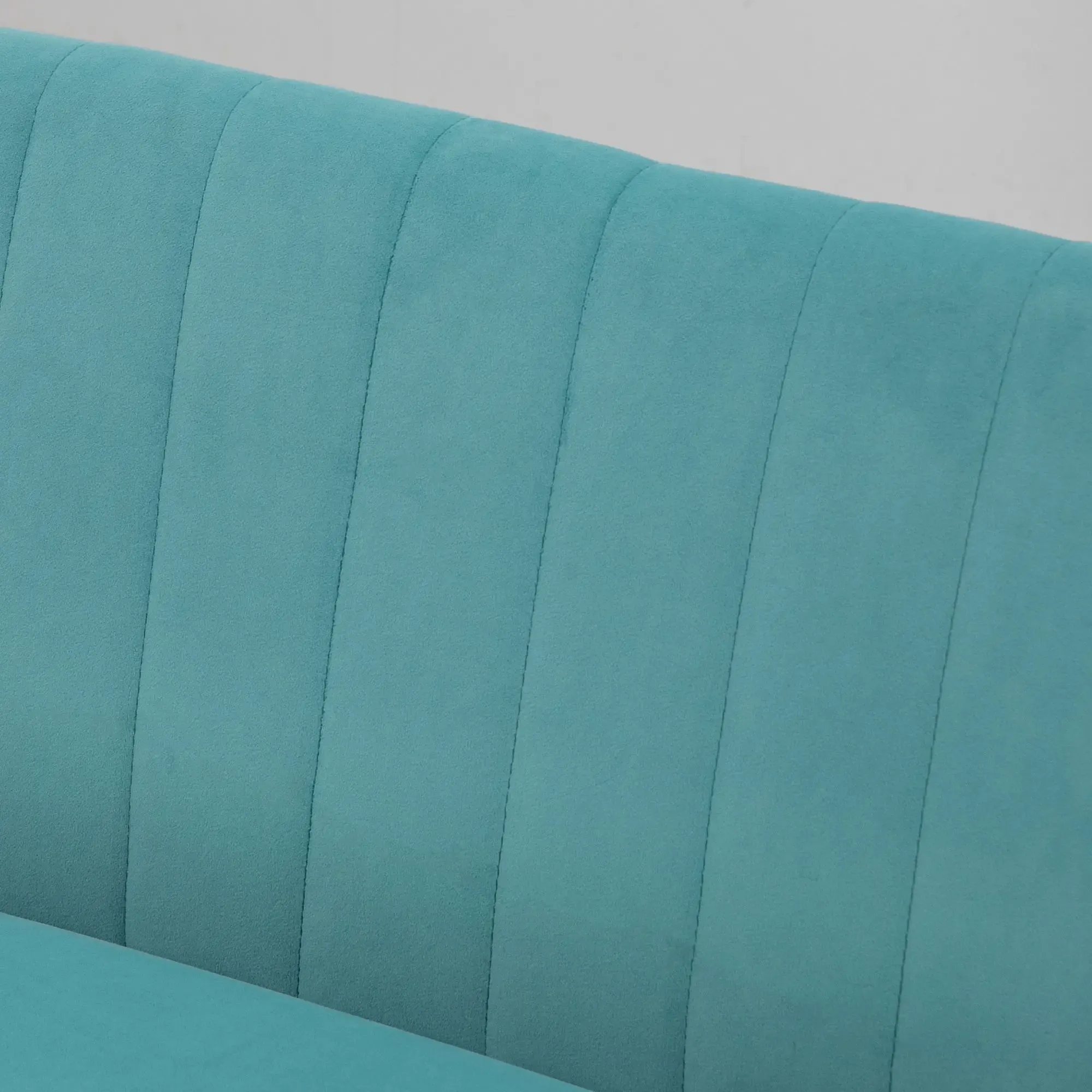 Nahaufnahme einer teal-farbenen Couchlehne mit vertikalen Stepplinien. Der Hintergrund ist schlicht weiß.