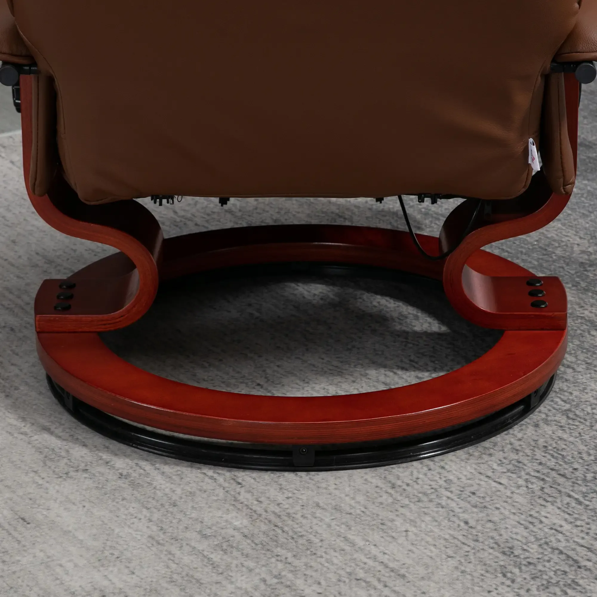 Brauner Leder-Relax-Sessel-Sockel. Er hat ein Holzgestell und einen schwarzen Sockel. Der Boden ist grau.