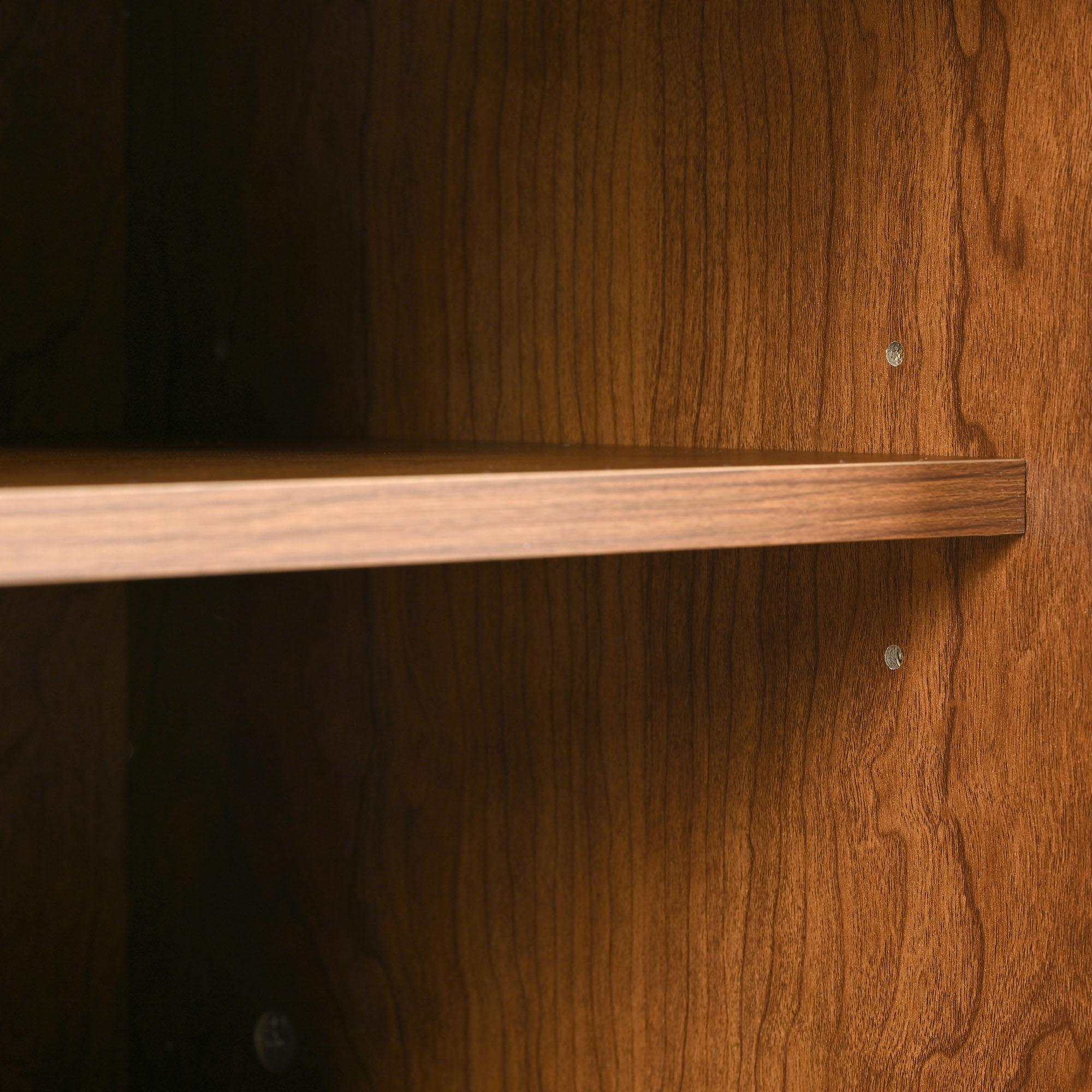 Innenraum eines Holzschranks. Ein Regal teilt den Raum. Die Holzmaserung ist sichtbar. Der Schrank ist dunkelbraun.