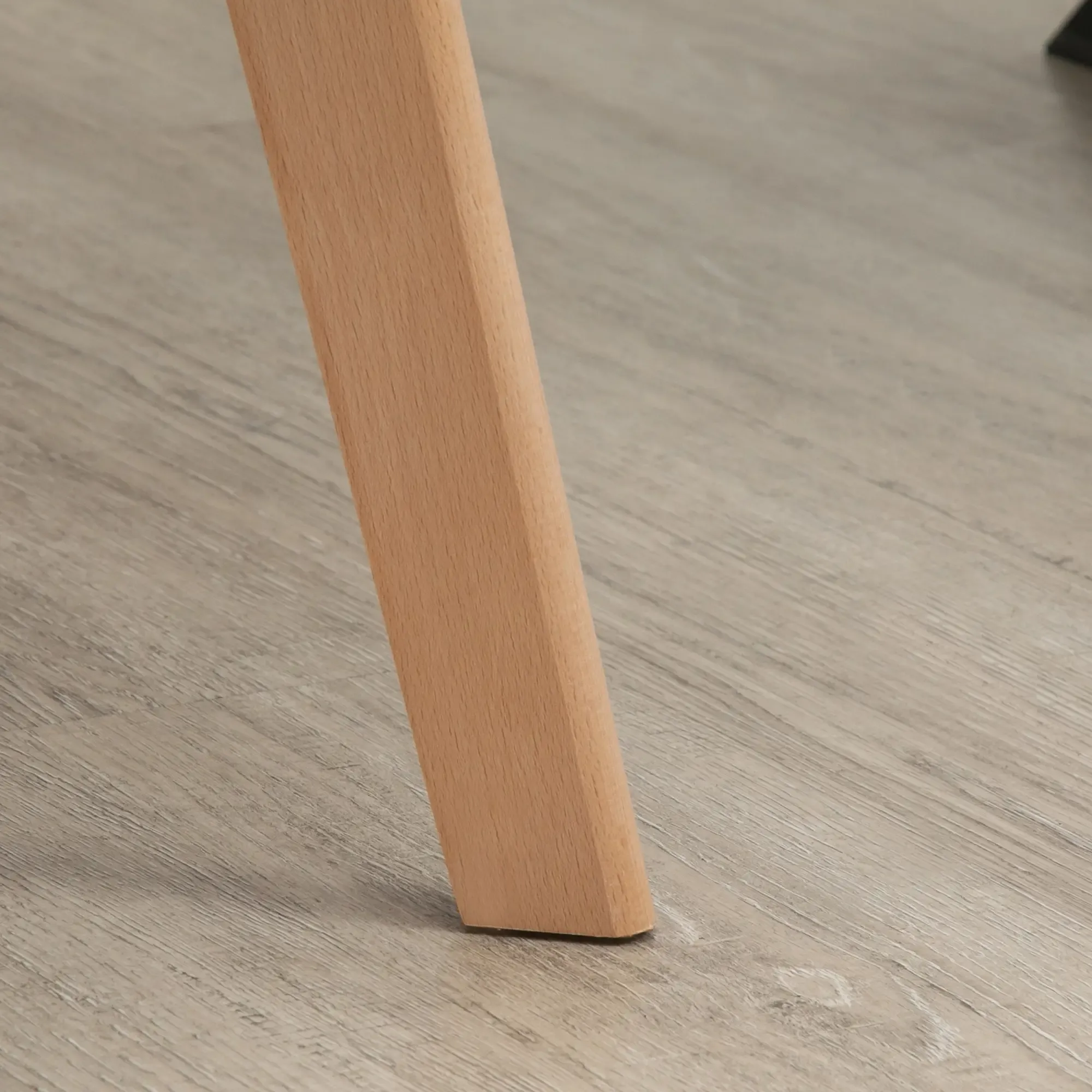 Ein Holzstuhlbein steht auf einem hellen Holzmaserboden. Das Bein ist hellbraun und abgewinkelt. Der Boden ist grau.