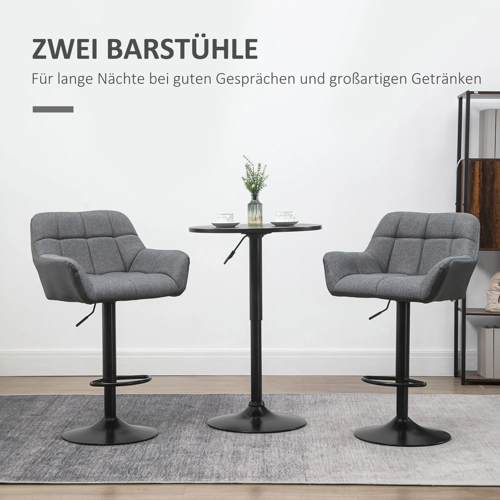 Zwei graue Barhocker mit einem kleinen Tisch, einer Pflanze und zwei Tassen darauf. Im Hintergrund eine weiße Wand.