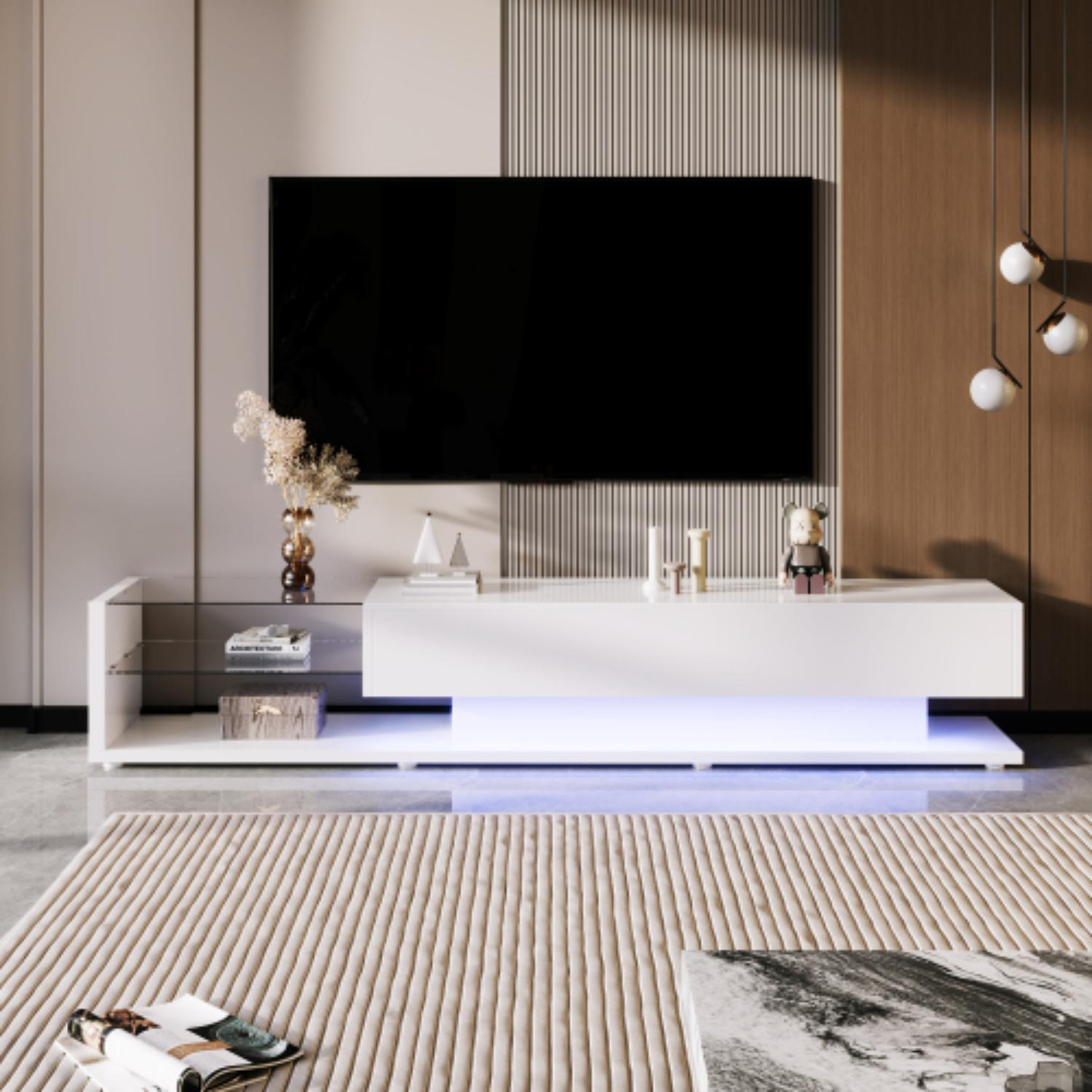 Modernes Wohnzimmer mit weißem TV-Ständer, großem schwarzem Fernseher und beigem Teppich. Deko-Artikel auf dem Ständer und eine Pflanze.