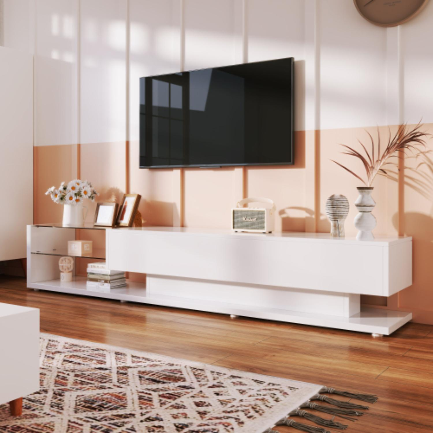 Ein modernes Wohnzimmer mit großem Fernseher, weißen Möbeln, Blumen und einem gemusterten Teppich auf Holzboden.